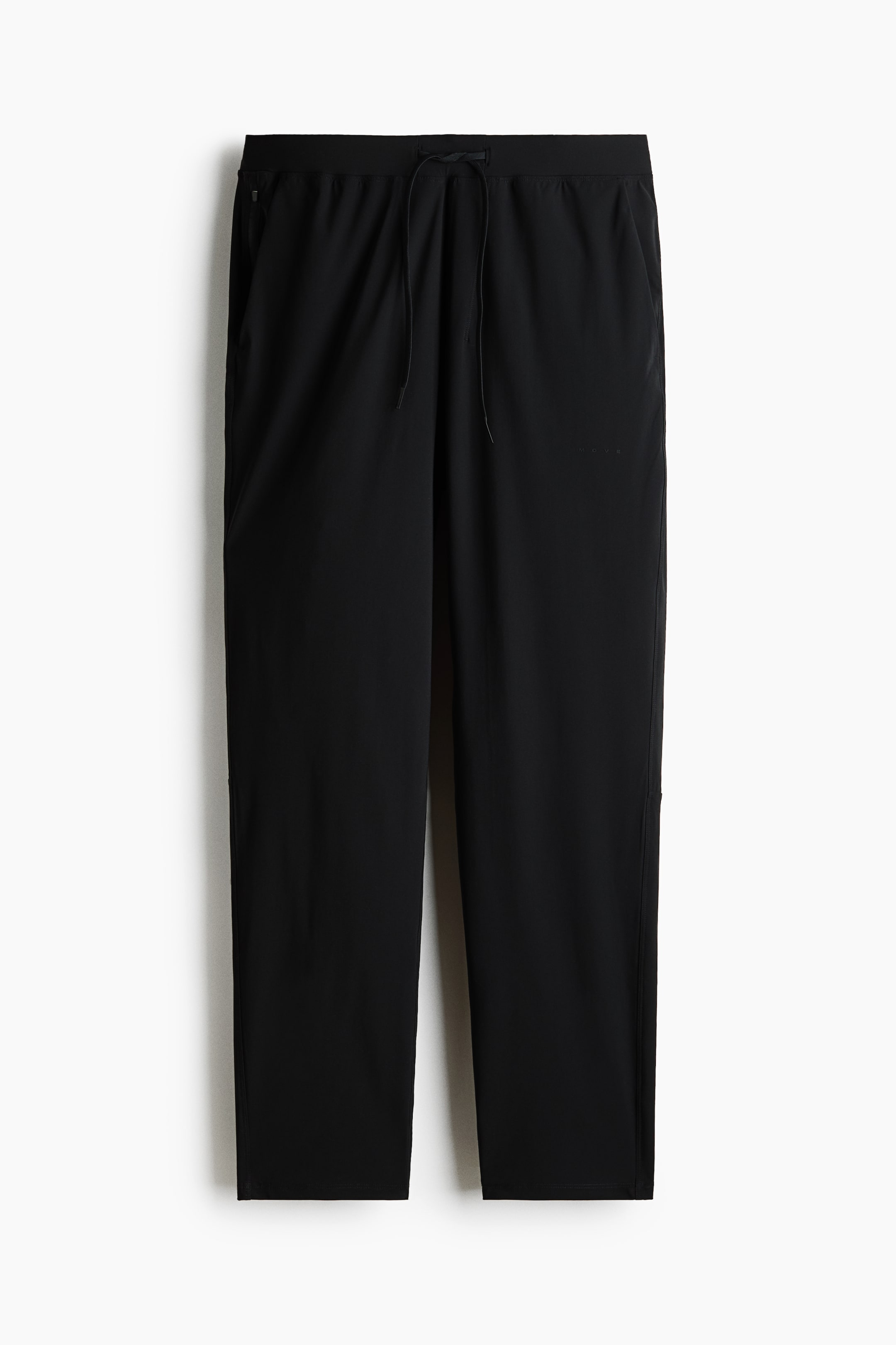 View larger image: Black pants feature an elastic waistband with a visible drawstring and side pockets, with a zippered closure visible on the left pocket. A subtle "ROOV" text appears on the upper right leg, and the straight legs show vertical seams along their outer sides, finishing with plain hems.