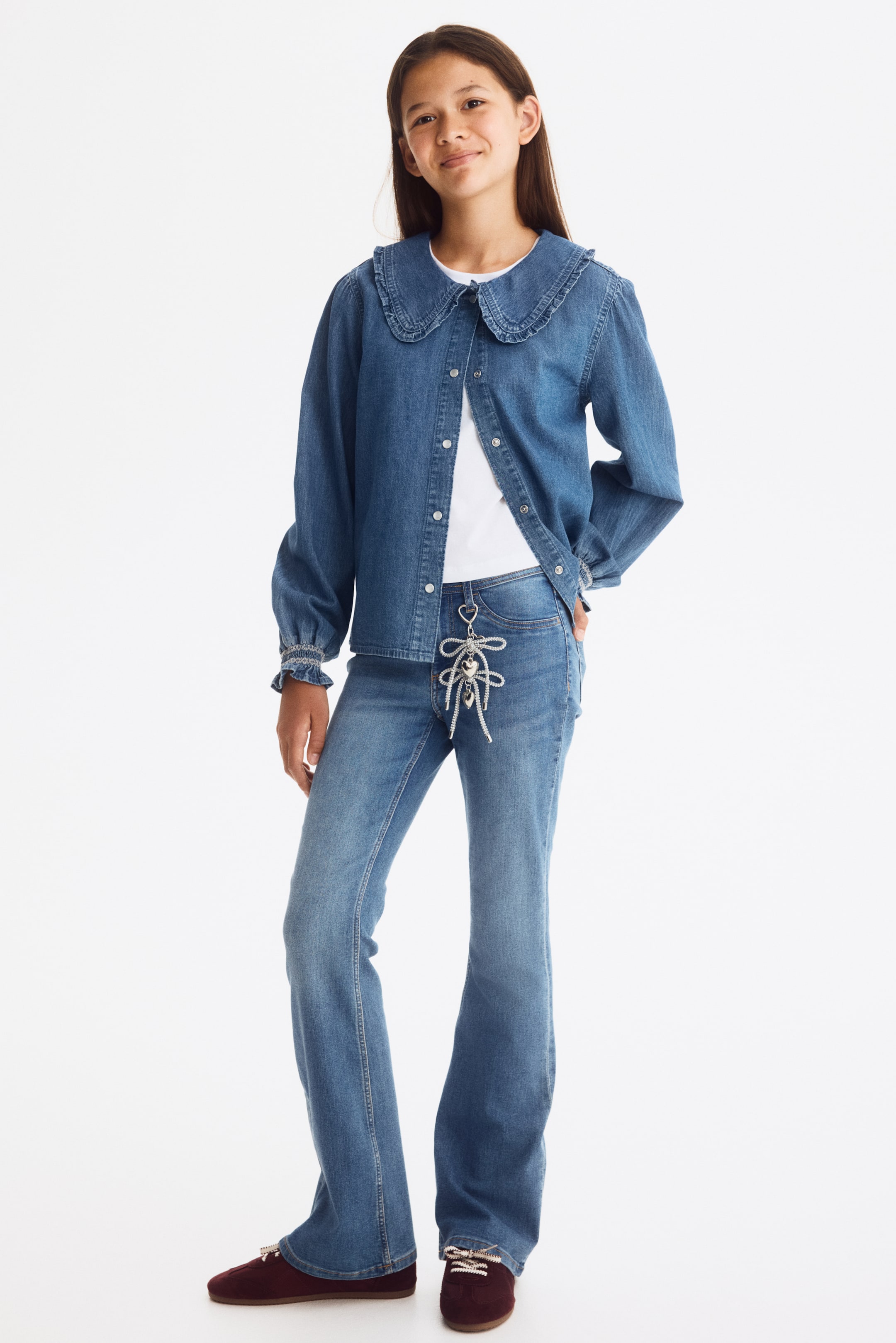 View larger image: Jeans are shown from the front, featuring a light blue denim wash with a skinny fit through the hip and thigh, flaring into flared legs. They are designed with a low waist, a front button fastening, faux front pockets, and open back pockets.