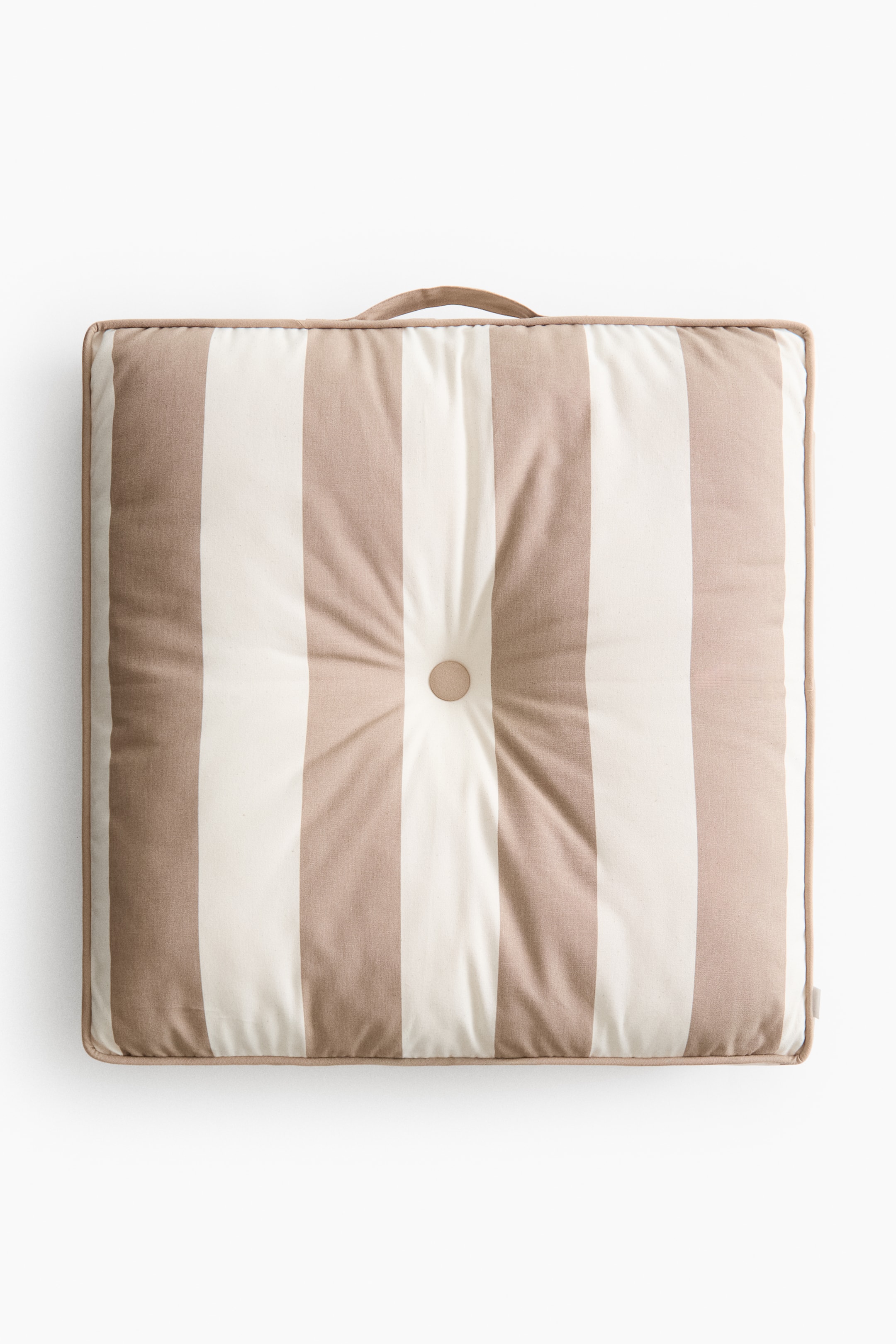 Ampliar la imagen: Un cojín cuadrado para el suelo presenta su parte frontal, con franjas verticales alternas en beige y blanco roto, un botón central con capitoné y una asa de tela para transportar en su borde superior.