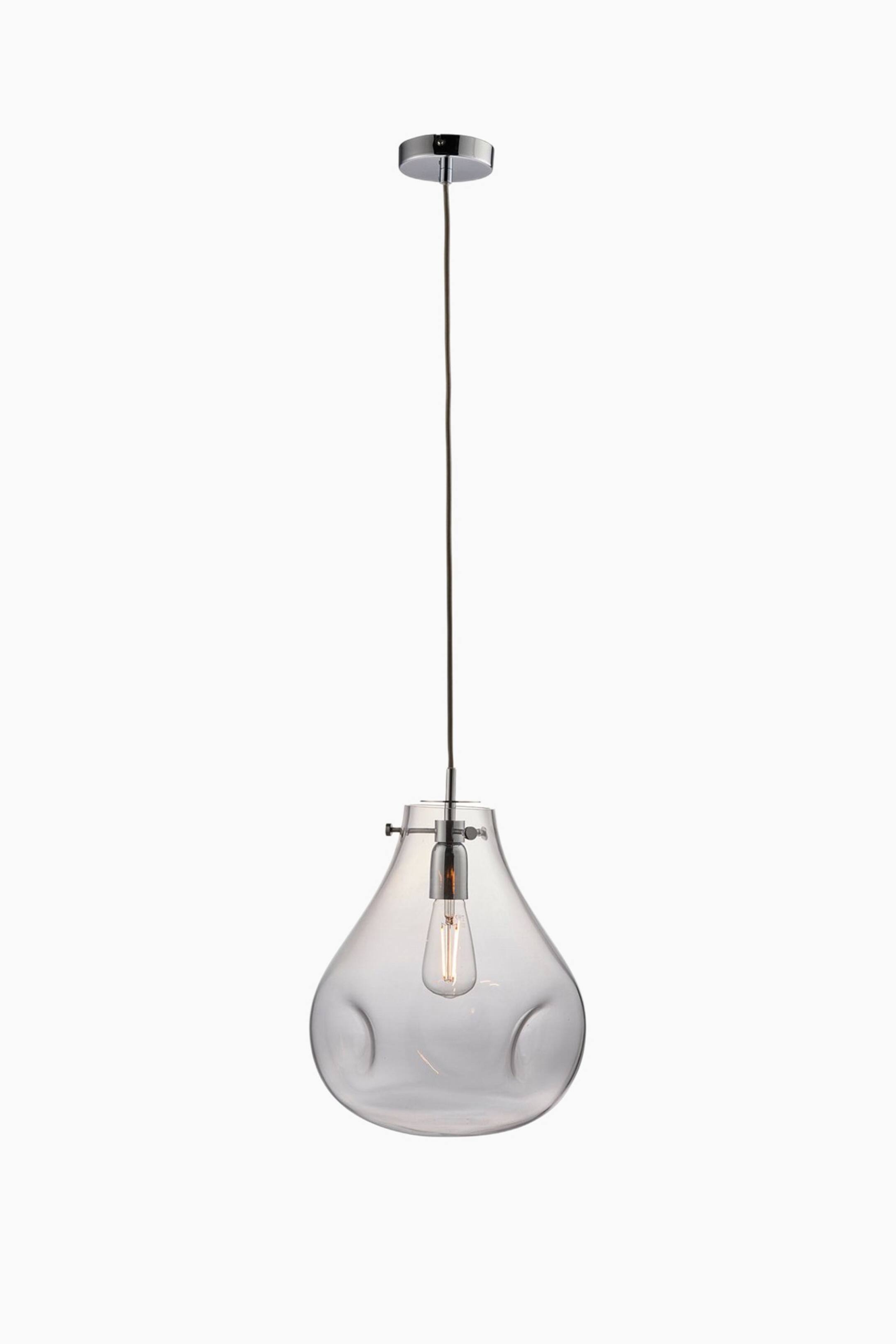 View larger image: A pendant light is hanging straight on, featuring a chrome ceiling canopy and a dark suspension cord. Its clear, organically shaped glass shade features subtle indentations and encloses an Edison-style filament bulb.