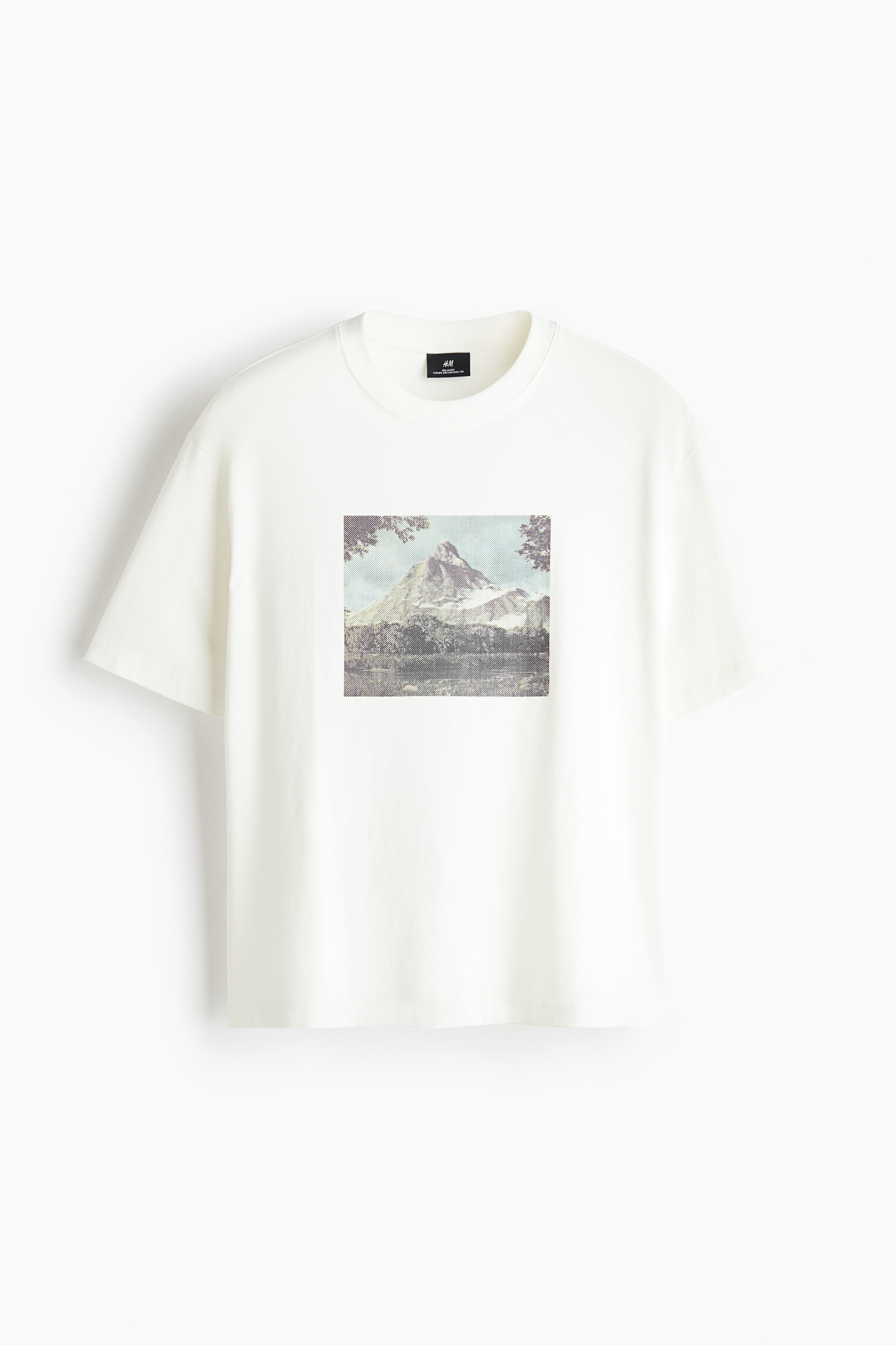 The model is wearing an off-white midweight jersey T-shirt featuring a square graphic print of a mountain landscape. The relaxed-fit tee features a round ribbed neckline, dropped shoulders, and a straight hem, and is paired with dark blue jeans.