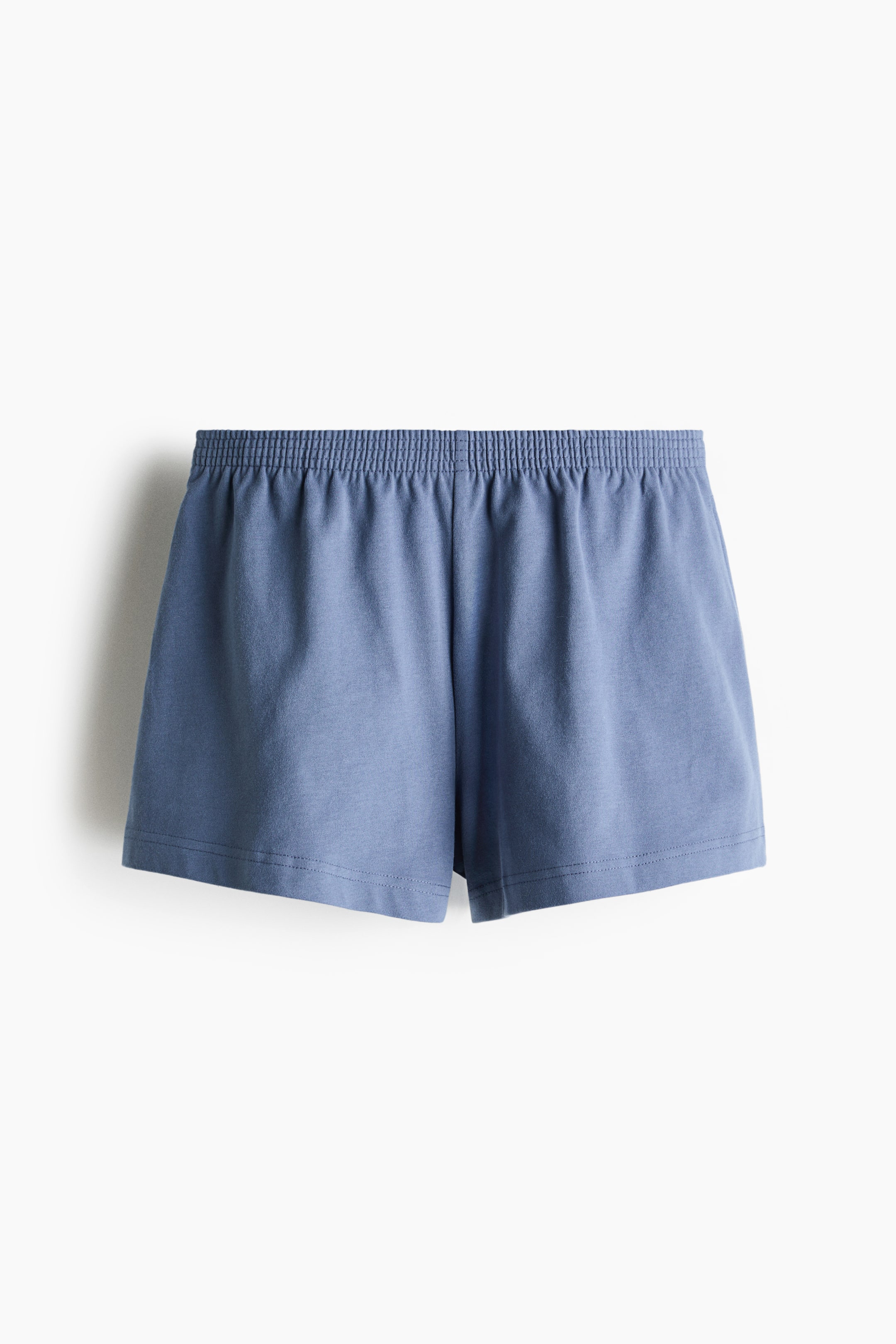 Größeres Bild anzeigen: Blaue Shorts werden von vorne präsentiert, gefertigt aus einem weichen Baumwoll-Jersey-Stoff und ausgestattet mit einem elastischen, gesmokten Bund.