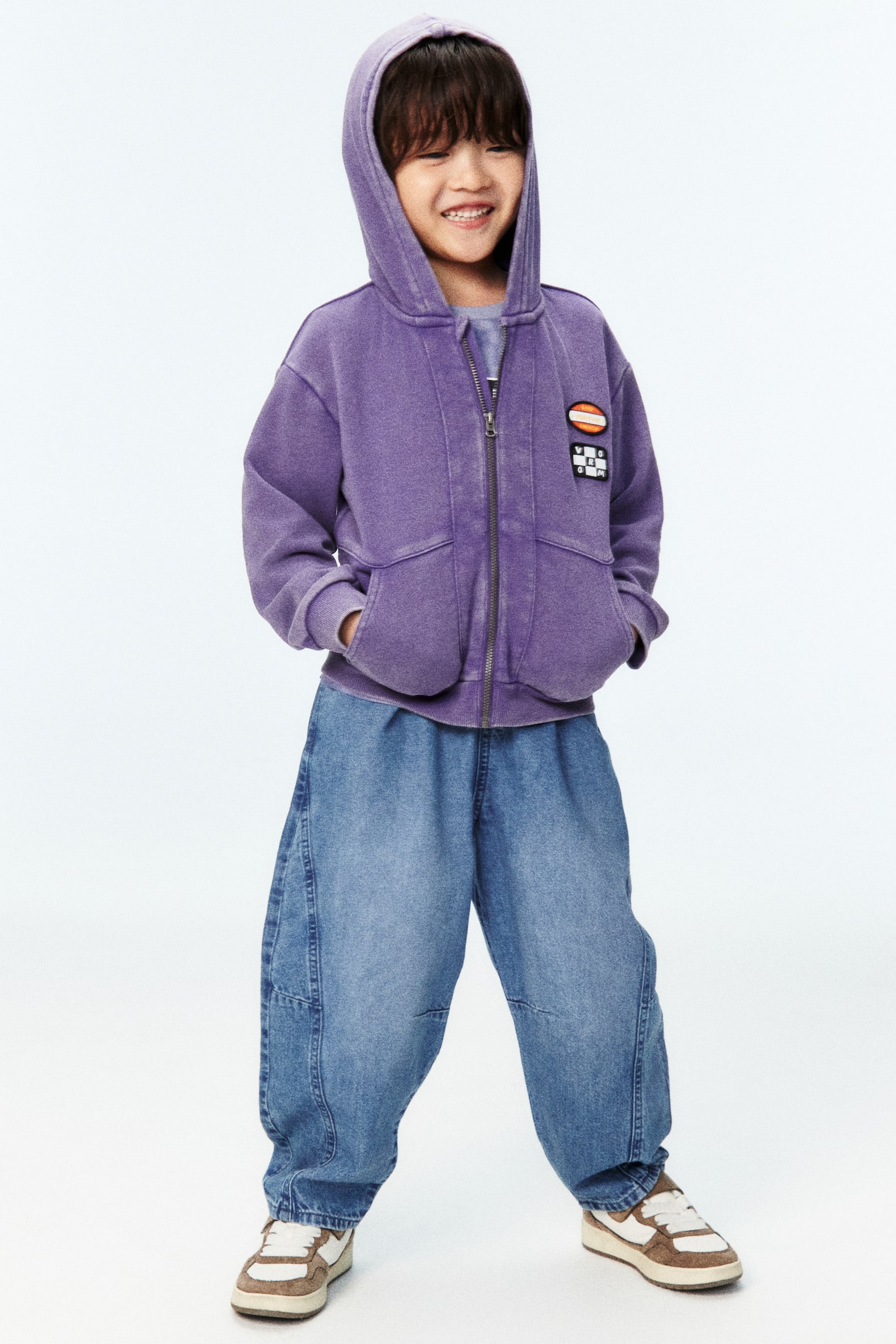 Light blue denim pants are showcasing a front view, designed with an elasticated waistband, two curved front pockets, and paneling crafted by diagonal seams on the outer legs and horizontal seams across the knees. - 1