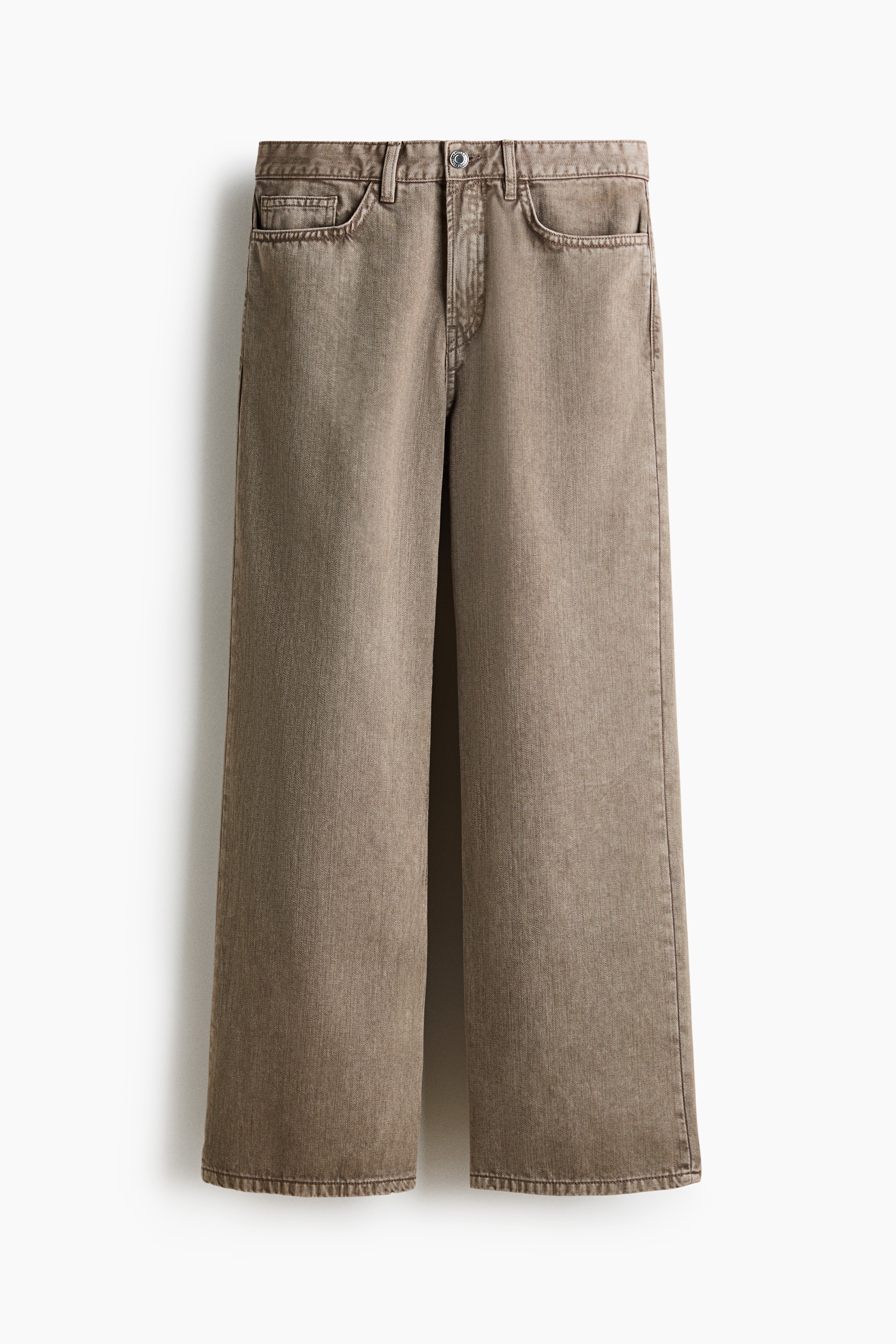 Relaxed-fit, five-pocket pants in brown cotton twill are worn by the model, who is standing with hands in their pockets. The straight-leg pants feature a silver-tone chain attached to a belt loop and are styled with a layered button-up shirt and black sneakers.