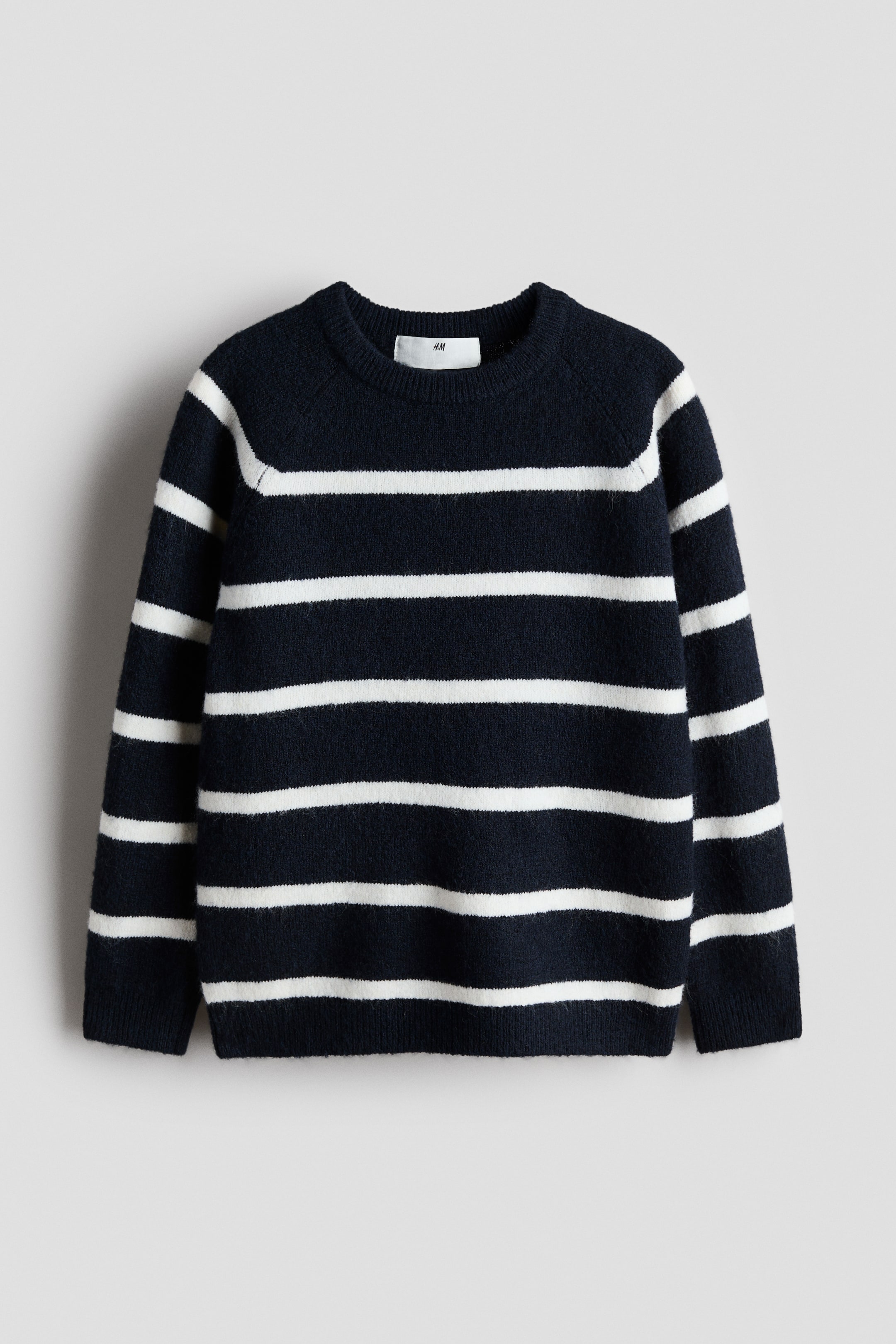 View larger image: A navy blue jumper is facing front, featuring white horizontal stripes, a crew neck, raglan sleeves, ribbed cuffs and hem, and a visible white H&M tag at the back of the neck.