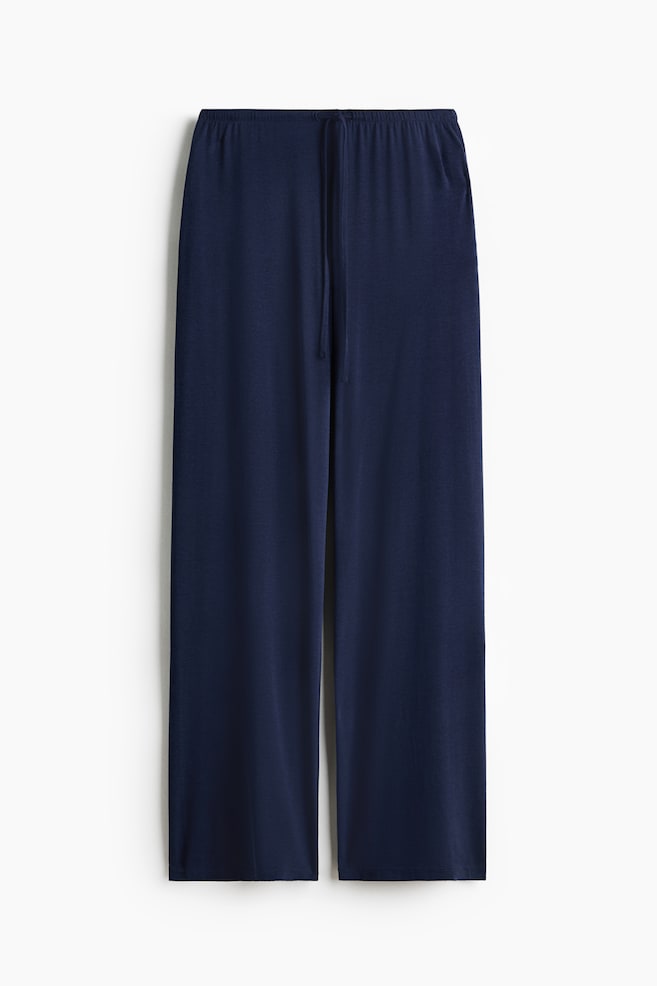 Dark blue trousers are showcasing a relaxed fit, complete with an elasticated, drawstring waist and wide legs. - 1