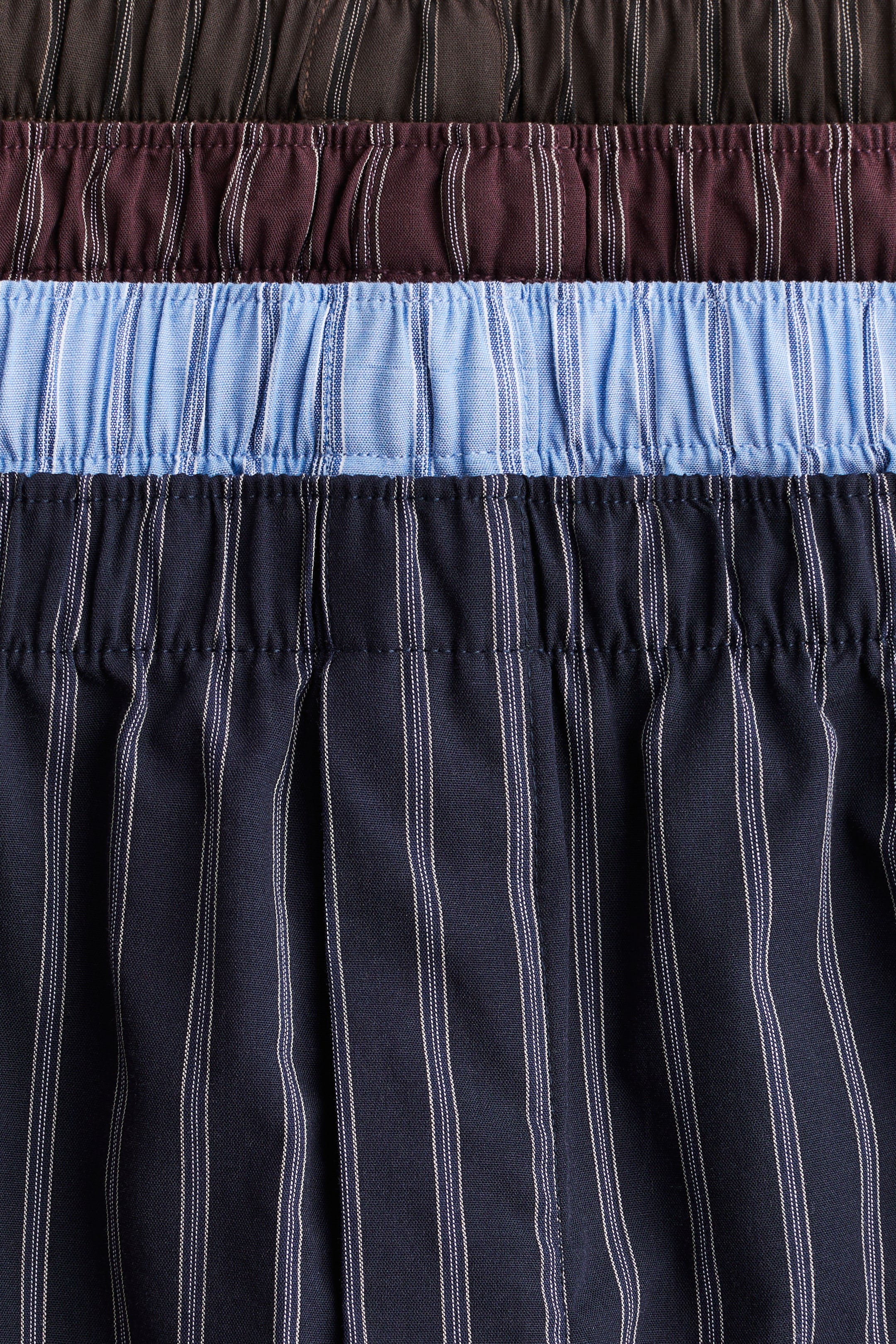 View larger image: Boxer shorts in a soft weave with an elasticated waist are being presented FRONT. Multiple pairs are showcasing their distinct colour and stripe patterns, including a dark brown pair with subtle vertical lines, and maroon, light blue, and navy pairs featuring prominent white vertical stripes.