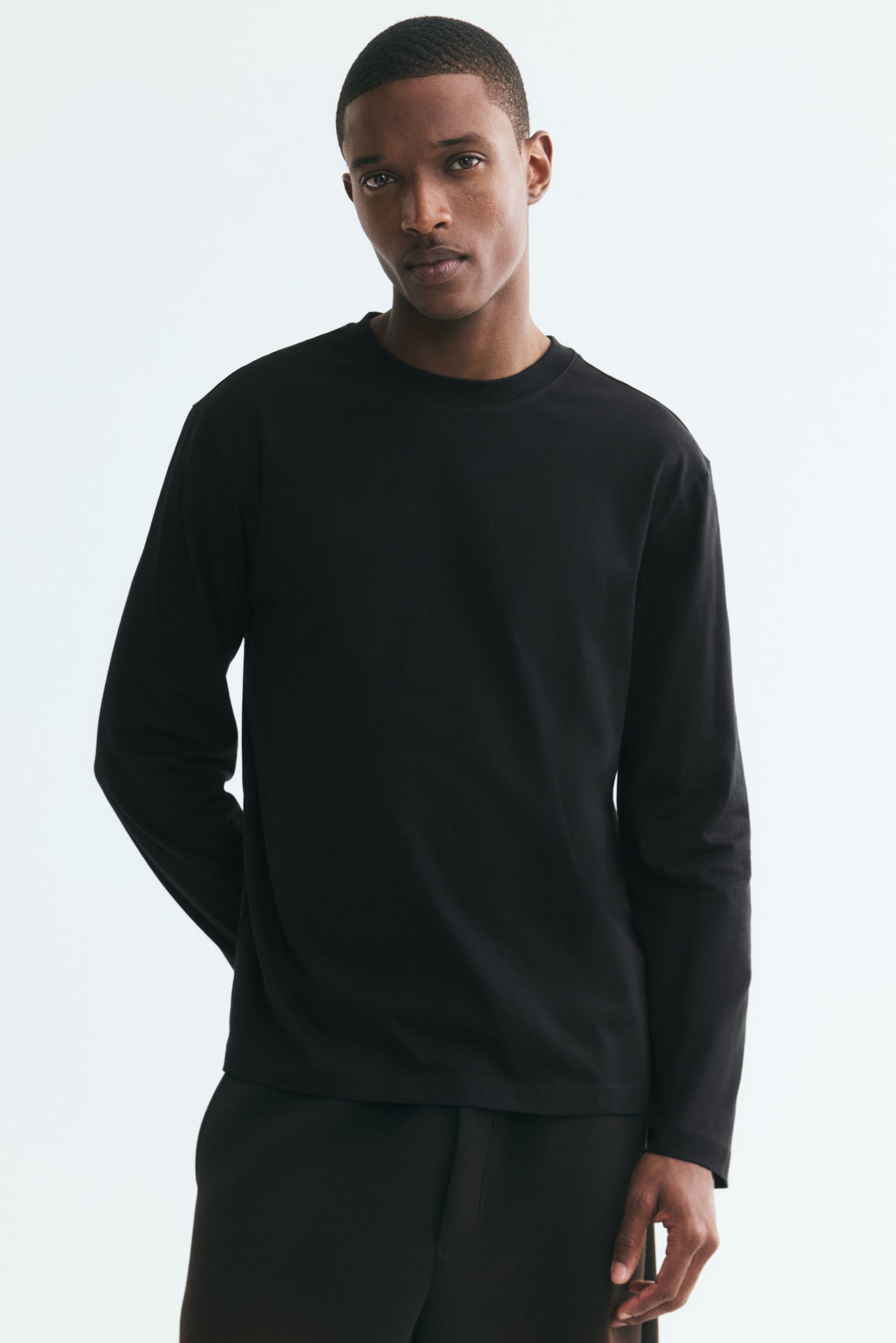 A black long-sleeved top is displaying its FRONT, featuring a round, rib-trimmed neckline and a straight-cut hem. - 1