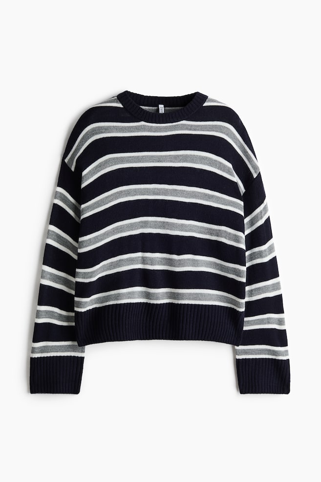 Een gebreide sweater met ronde hals wordt van voren getoond, met afwisselende horizontale strepen in marineblauw, grijs en wit. De sweater heeft verlaagde schouders, een geribbelde halslijn, een geribbelde zoom en brede geribbelde boorden. - 1