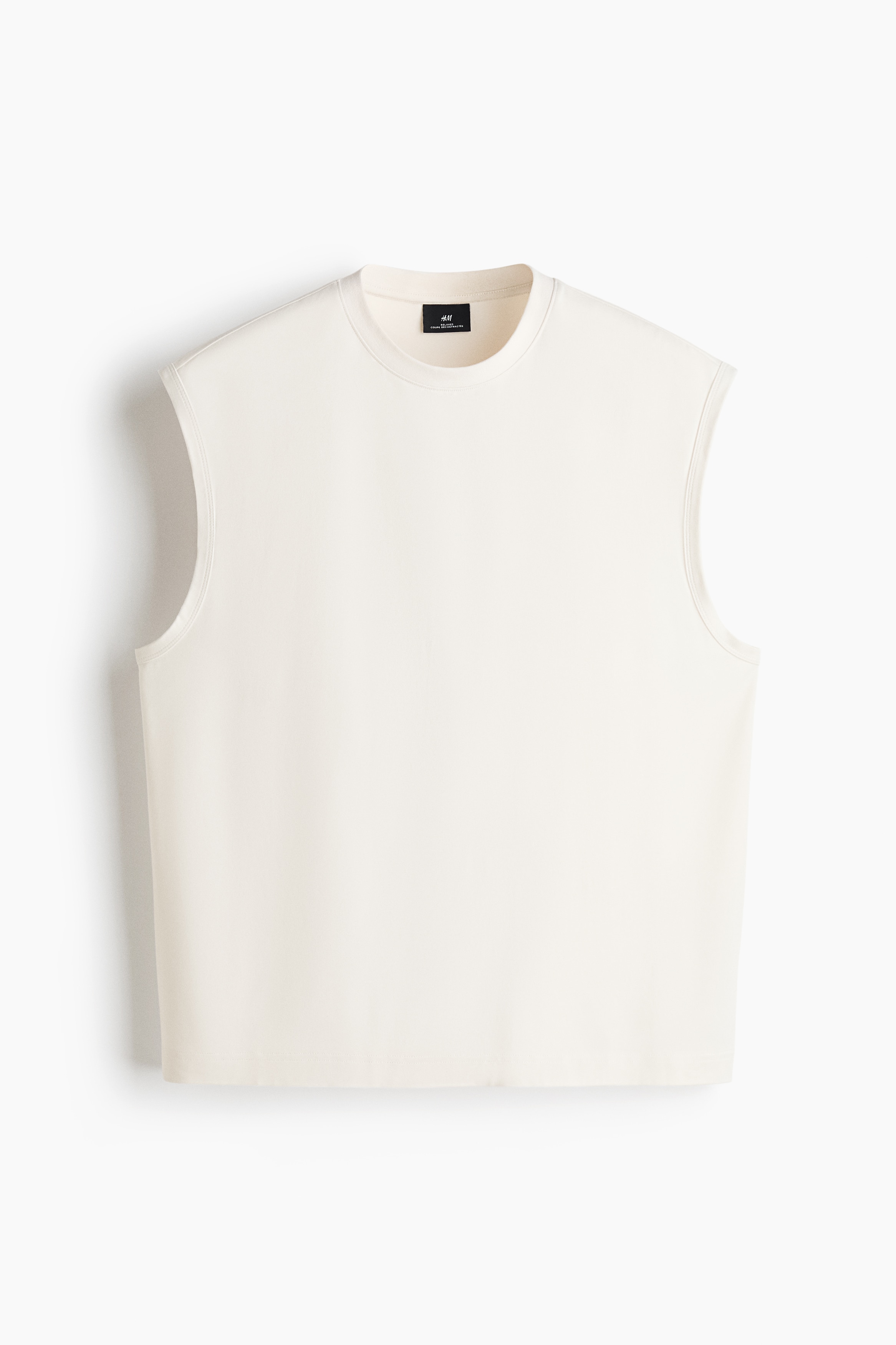 Le modÃ¨le porte un camisole blanc cassÃ© Ã  encolure ronde bordÃ©e de cÃ´tes et Ã  profondes emmanchures. Le haut Ã  coupe dÃ©contractÃ©e est rentrÃ© dans un pantalon de jogging blanc cassÃ© assorti avec cordon de serrage.