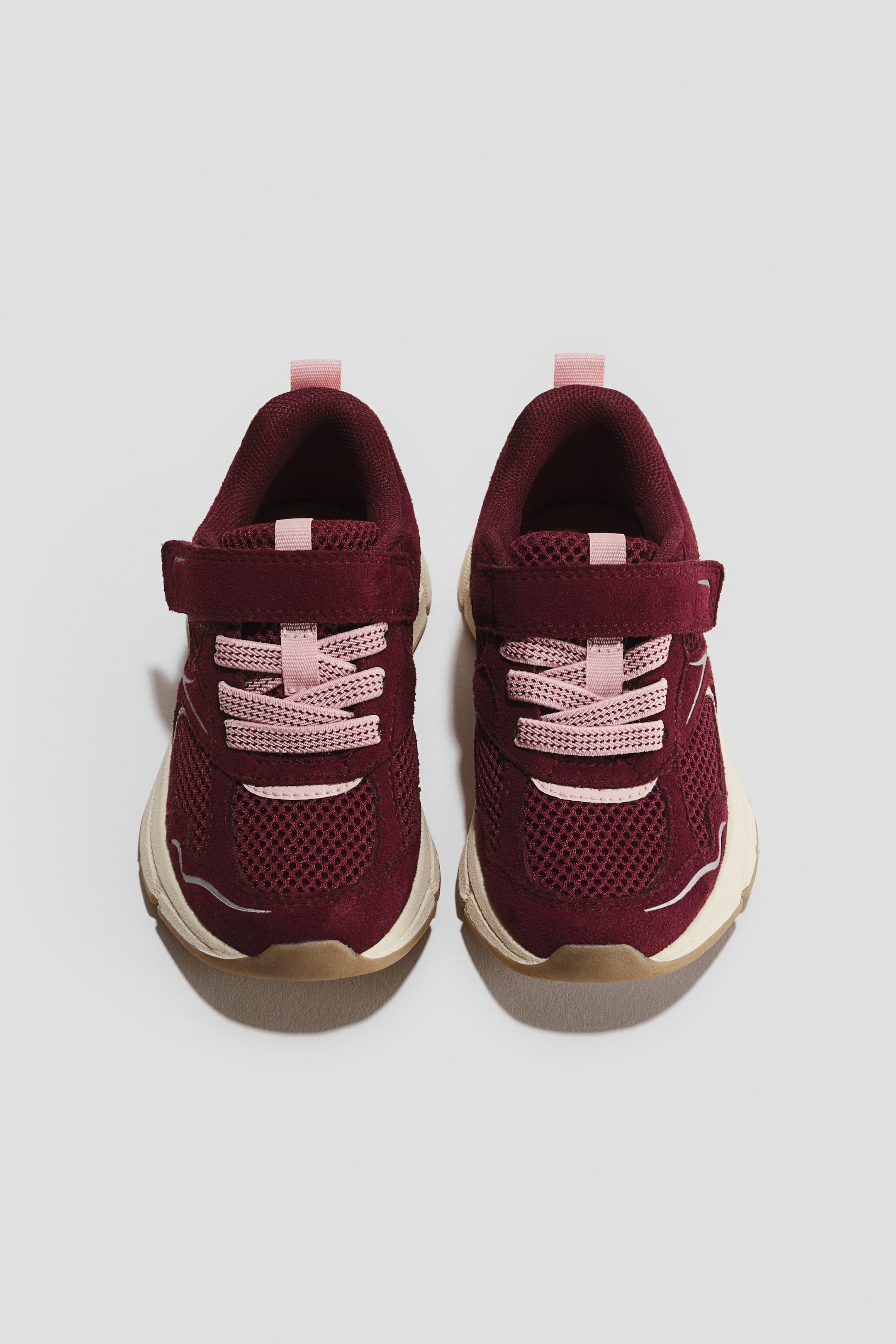 Näytä suurempi kuva: Burgundin ja vaaleanpunaisen sävyiset sneakersit on kuvattu ylhäältä päin eteenpäin suunnattuina. Niissä on teksturoidut mesh-paneelit mokkanahkaisilla päällysteillä, vaaleanpunaiset joustavat nauhat tarrakiinnitteisen remmin alla sekä kermanväriset välipohjat ja kumipohjat.