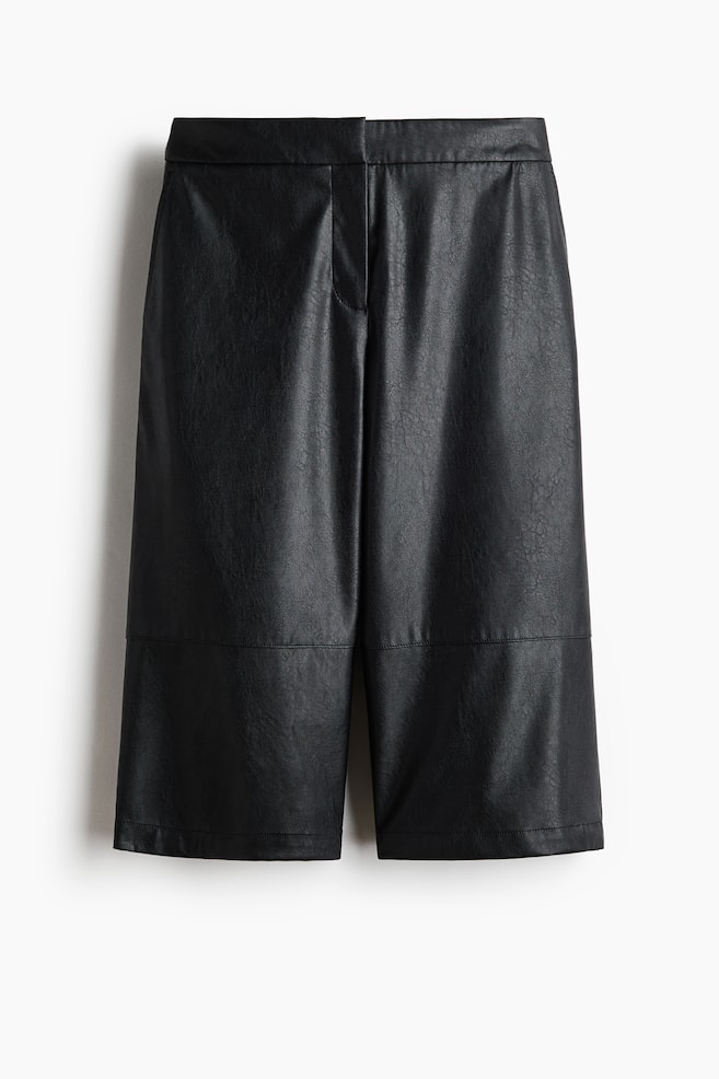 Black faux leather Bermuda shorts are presenting their front, featuring a subtly crinkled surface and a flat waistband. They are displaying a subtle fly closure and horizontal paneling seams across the lower legs. - 1