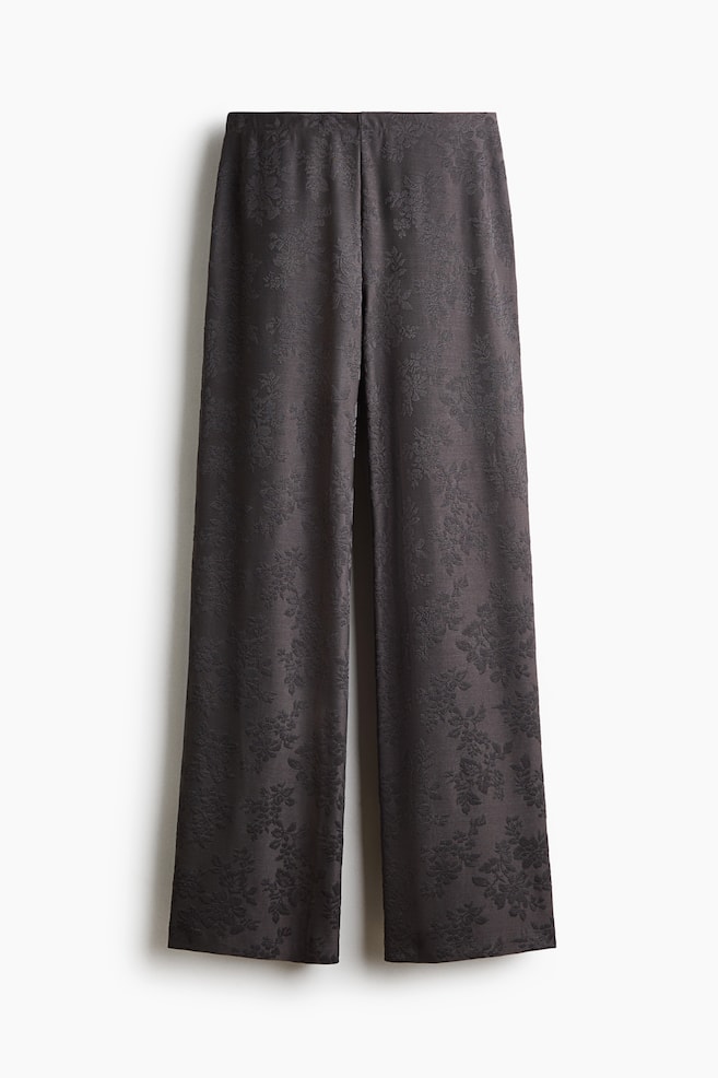 Eine Hose aus dunkelgrauem Stretch-Jacquard-Jersey ist in einer Frontansicht dargestellt und verfügt über ein dezentes strukturiertes Blumenmuster, einen hohen elastischen Bund und einen geraden Beinverlauf. - 1