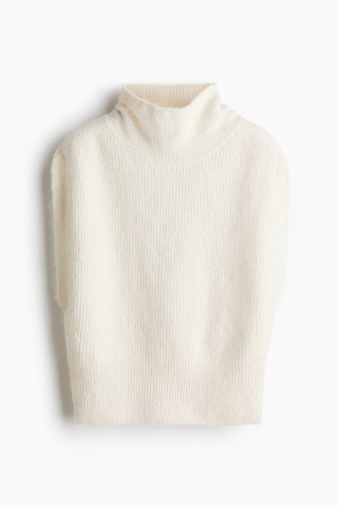 A cream sleeveless jumper is showcased from the front, featuring a ribbed polo neck and a soft, vertically ribbed knit body. - 1