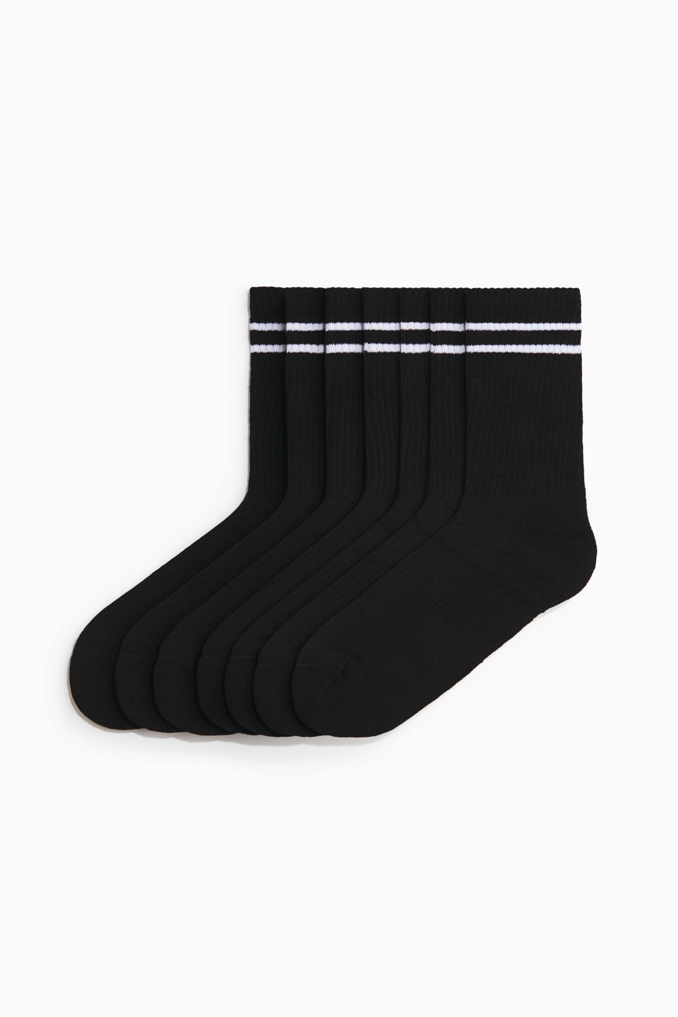 Voir une image plus grande: Six chaussettes noires à coupe basse sont présentées, empilées et étalées en éventail vers la gauche, avec les orteils pointant vers la droite. Chaque chaussette arbore des poignets côtelés rehaussés de deux bandes blanches.