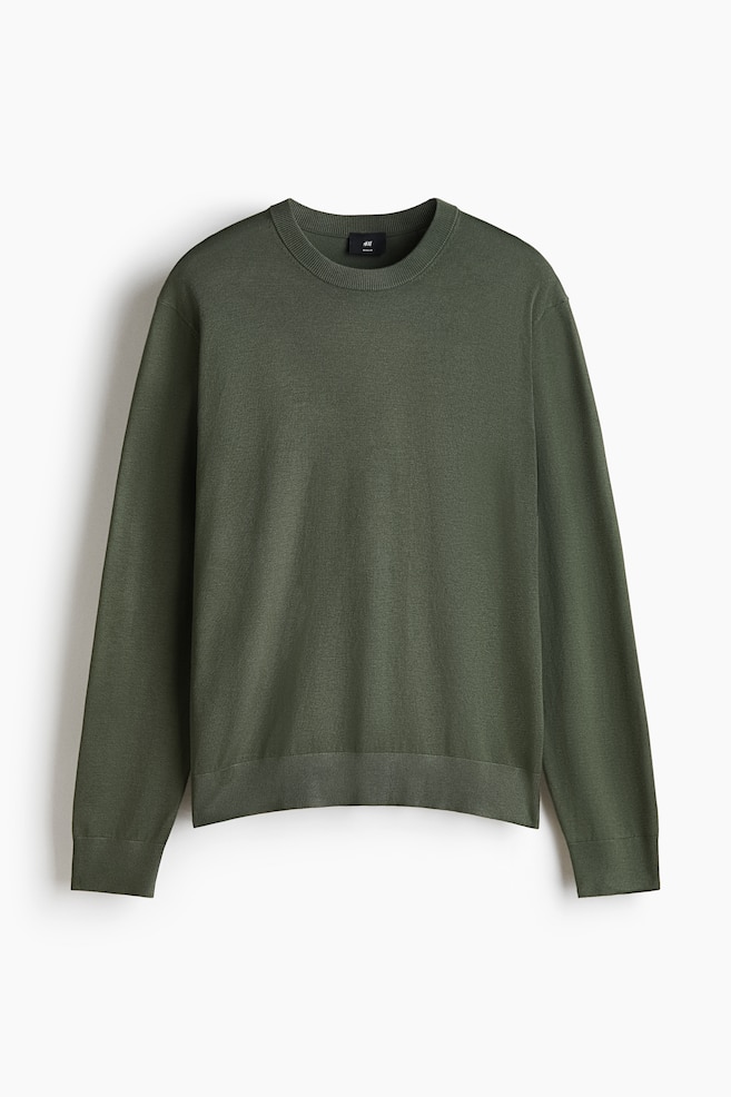 An olive green fine-knit jumper is shown from the front, featuring a regular fit with a classic silhouette. It has a round, rib-trimmed neckline, long sleeves with ribbed cuffs, and a matching ribbed hem. - 1