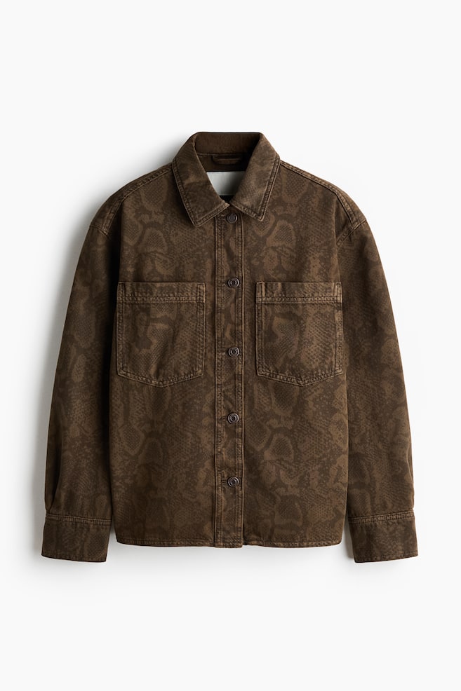 A brown shirt jacket is displayed flat, featuring a subtle, tone-on-tone snakeskin pattern. It is designed with a classic collar, a button-front closure, two chest flap pockets, and buttoned cuffs. - 1