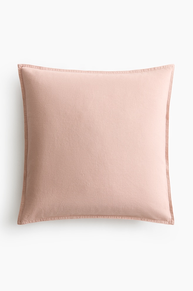 Uma capa de almofada apresenta a sua frente, com um tecido de linho e algodão em rosa claro. É detalhada com costuras visíveis ao longo das laterais. - 1
