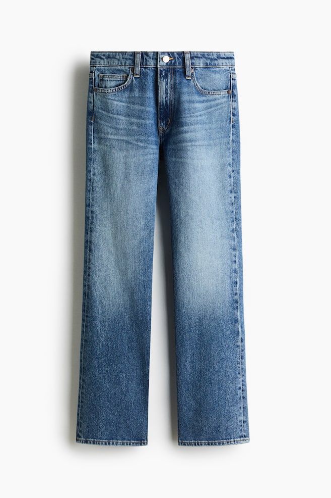 A pair of blue denim jeans is shown from the front, featuring a classic five-pocket design with a button and zip fly fastening at the waistband. The jeans display a faded wash down the thighs and a bootcut leg silhouette that flares slightly at the hem. - 1