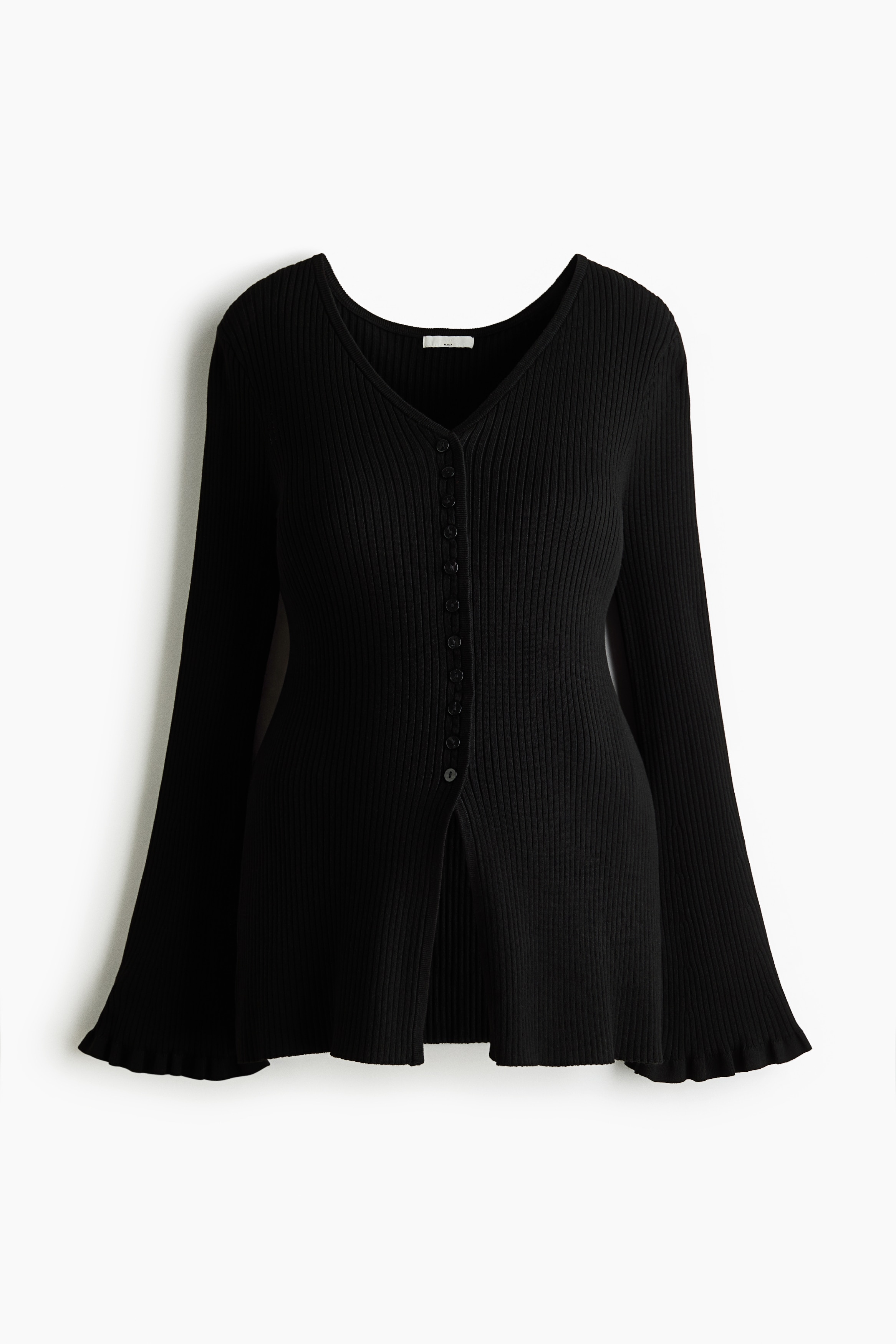 A long, black, fitted rib-knit cardigan featuring a V-shaped neckline, front button closures, and long sleeves with frill-trimmed cuffs is worn by the model. The model is pairing the cardigan with matching black rib-knit trousers, posing with one arm crossed over the torso and one hand resting under the chin.