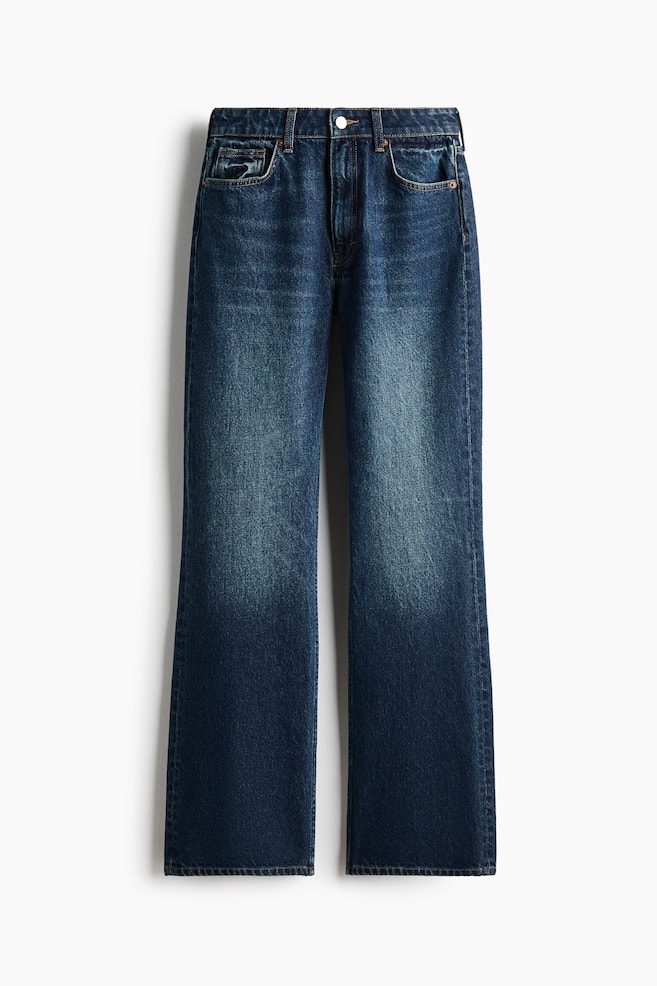 Un par de jeans rectos de color azul oscuro está de frente, mostrando un lavado deslavado en los muslos y un diseño clásico de cinco bolsillos. Los jeans presentan una cintura de tiro alto con trabillas para cinturón y un cierre de un solo botón metálico. - 1