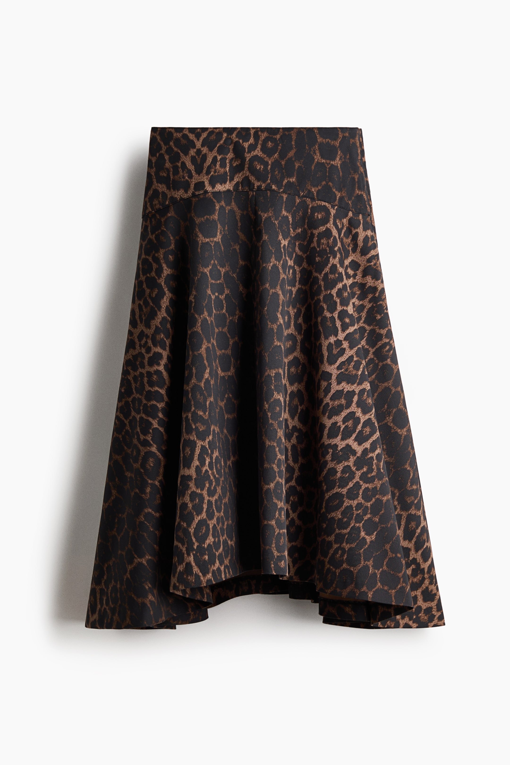 View larger image: The front of the skirt features a black and brown leopard print. It has an A-line silhouette with a wide waistband and a flowing, asymmetrical hemline.