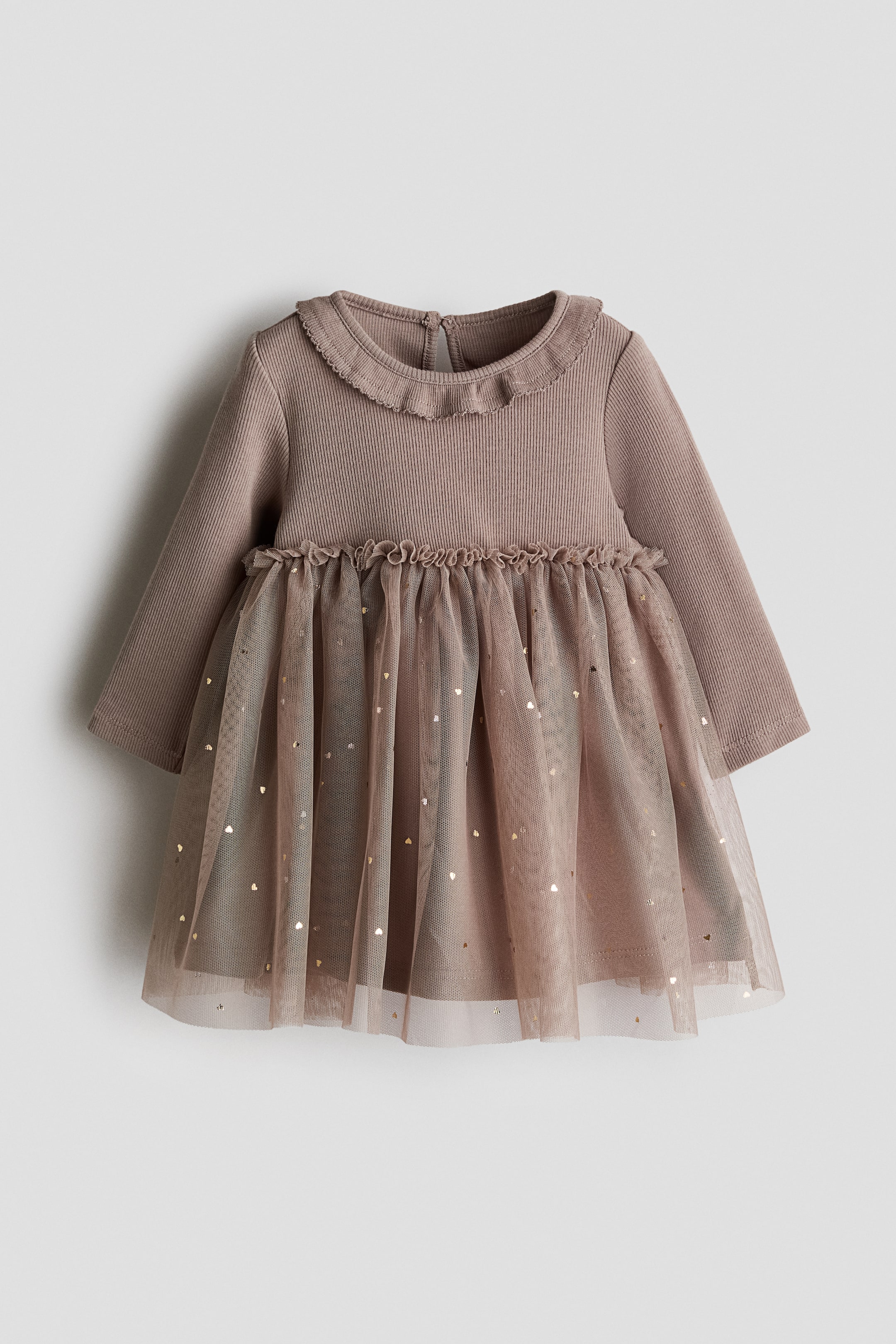 Voir une image plus grande: Cette robe pour bébé présente un corsage en tricot côtelé taupe avec des manches longues et un col rond à volants. Une ouverture en goutte d'eau est visible à l'arrière du cou, et une jupe en tulle froncée, ornée de cœurs dorés éparpillés, complète la robe.