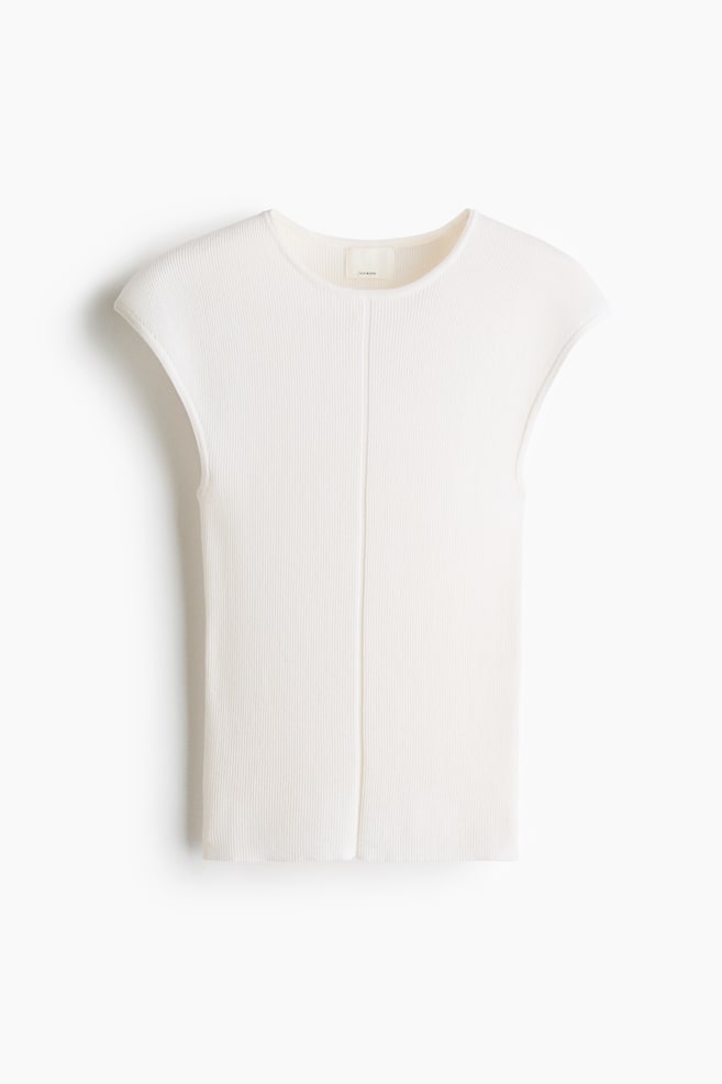 A cream ribbed knit cap-sleeve top is presented, featuring a round neckline and a prominent vertical seam running down its centre front. - 1