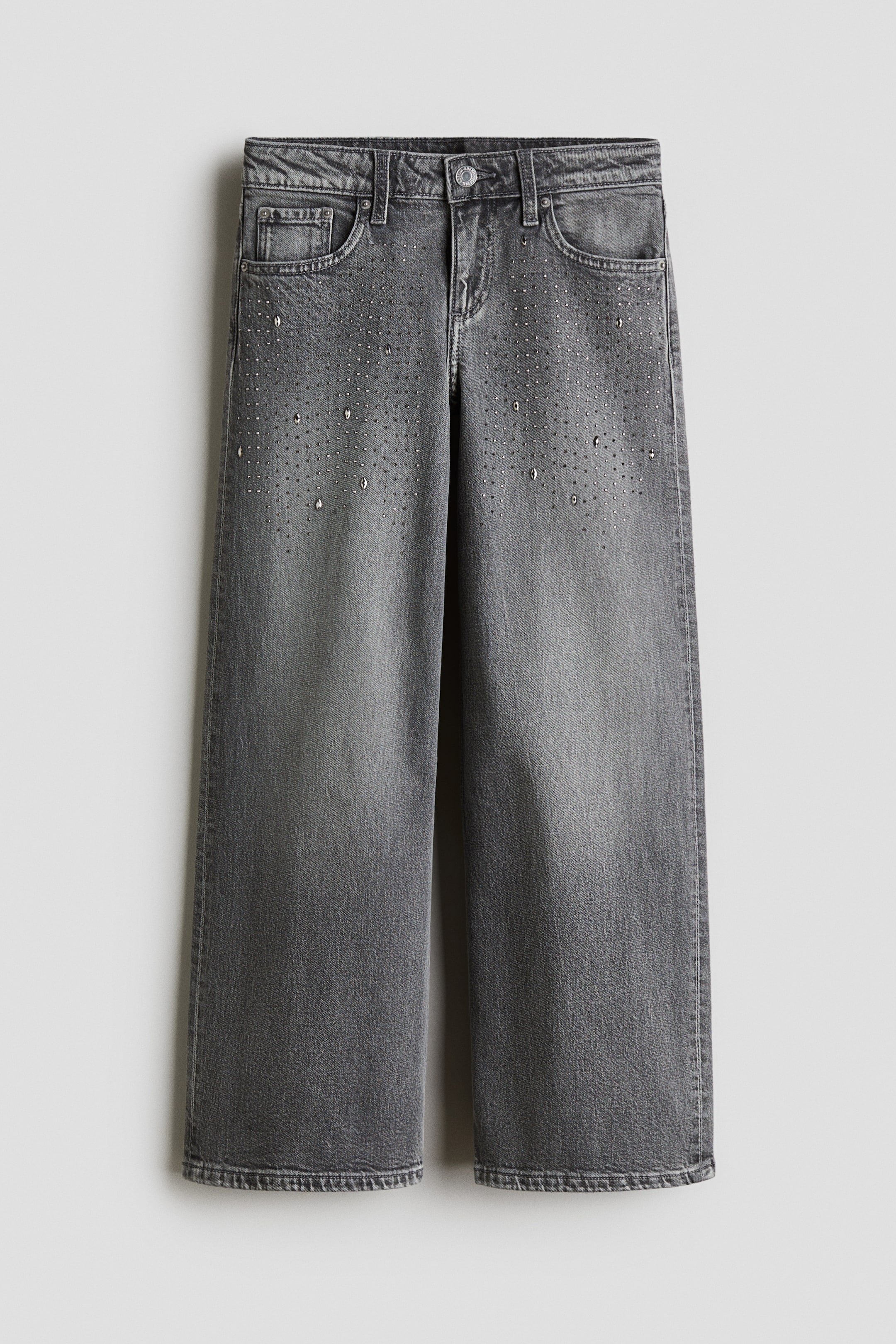 View larger image: The FRONT of a pair of 5-pocket jeans is being displayed, crafted from washed-out gray cotton denim. They are featuring a low waist, a zip fly with button closure, a relaxed fit through the hip, thigh, and leg, and small metallic studs scattered across the upper front.