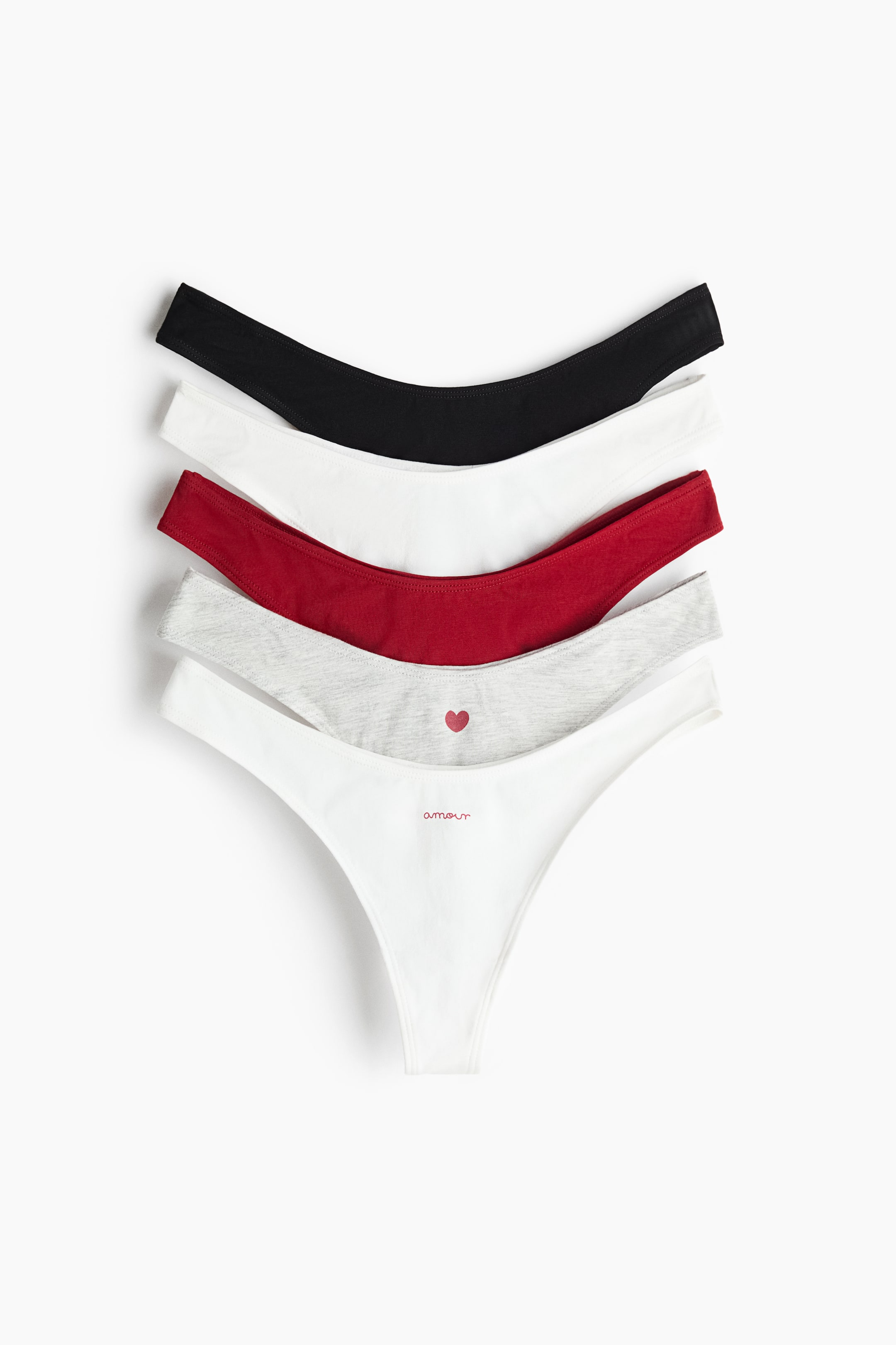 Grotere afbeelding bekijken: Meerdere slips met string in katoenen jersey zijn opgestapeld en waaierend opgesteld, met de voorkant zichtbaar en een lage, V-vormige taille. De slips zijn uitgevoerd in zwart, wit, rood en gemêleerd grijs, waarbij één witte slip de letters 'amour' heeft en één grijze slip een klein rood hartje toont.