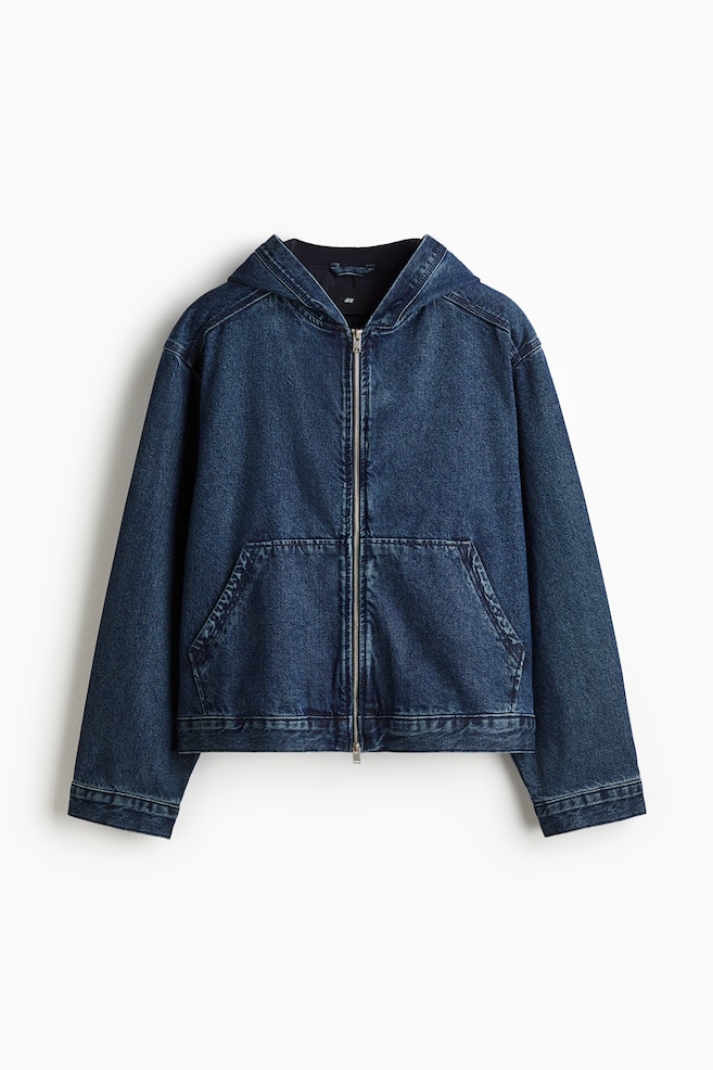 A dark blue, rigid denim jacket is presenting its FRONT, featuring a dark cotton-lined hood and a silver-toned zip closure down the center. It is designed with long sleeves and two large patch pockets on the lower front, displaying a loose fit and a straight hem. - 1