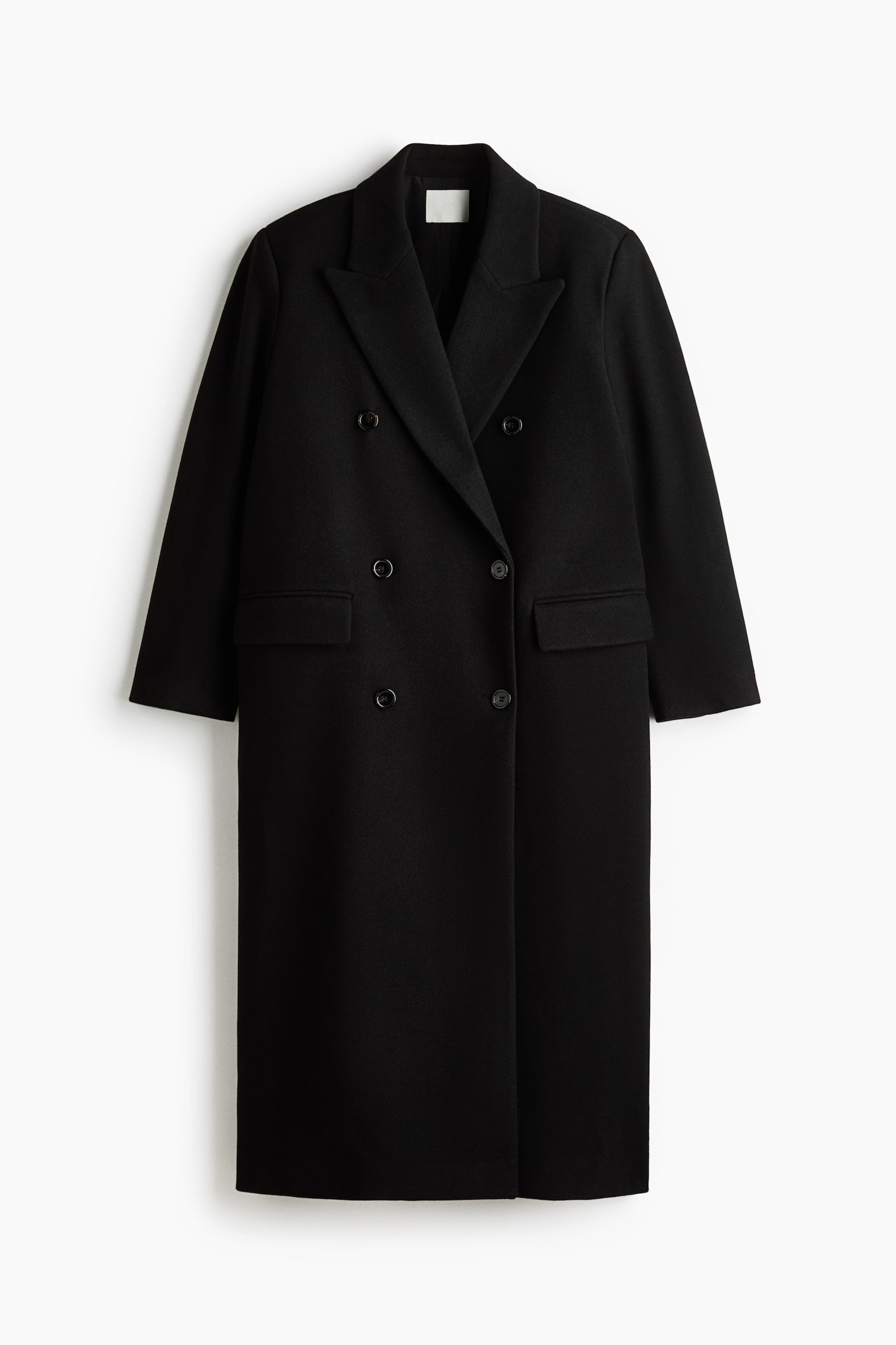 A long black double-breasted coat is shown from the front, featuring an oversized fit with wide peak lapels and a six-button fastening. The coat features jetted front pockets with flaps and long sleeves in a soft, felted fabric.