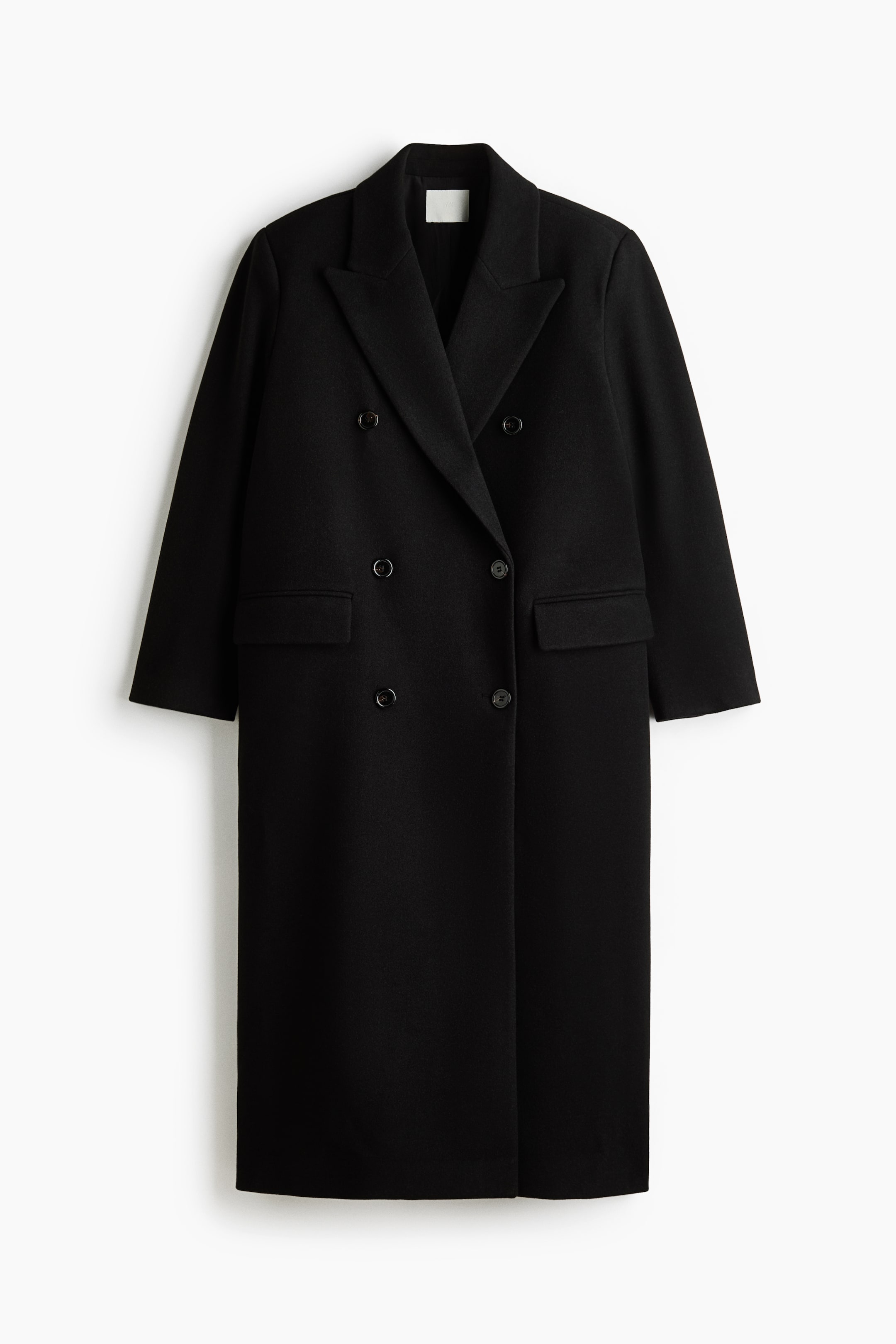 View larger image: A long black double-breasted coat is shown from the front, featuring an oversized fit with wide peak lapels and a six-button fastening. The coat features jetted front pockets with flaps and long sleeves in a soft, felted fabric.