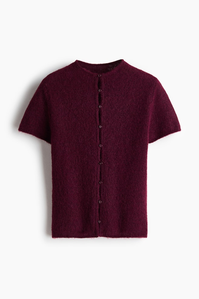 The burgundy fuzzy knit cardigan is shown front-facing, featuring short sleeves and a collarless round neck. A full button-front closure with small, color-matched buttons is running down the center. - 1