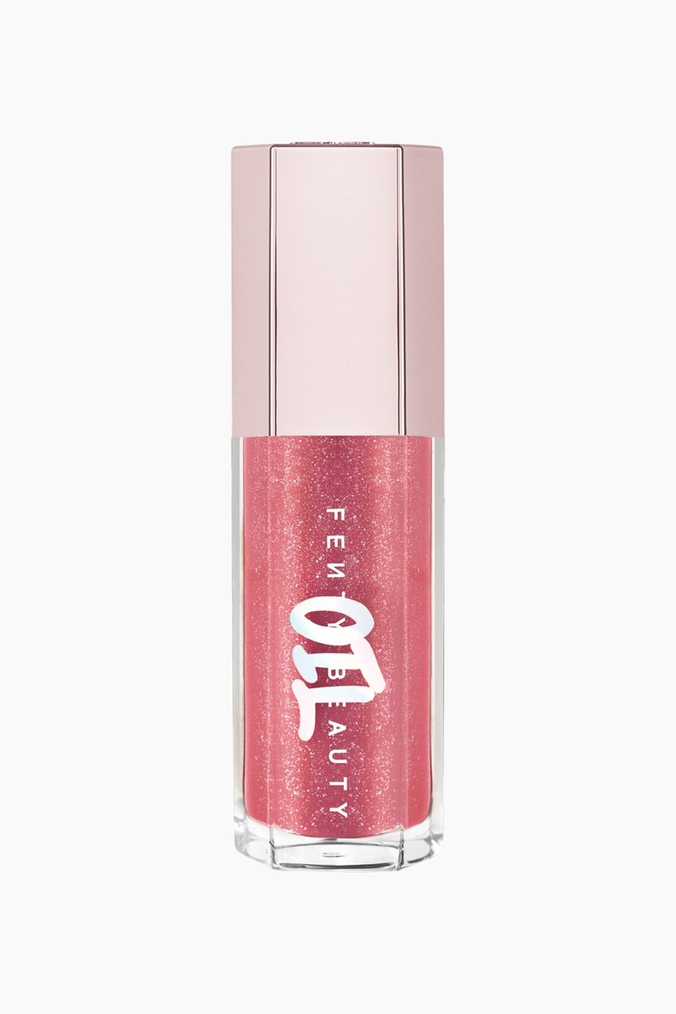 Visa större bild: Gloss Bomb Oil Luminizing Lip Oil 'n Gloss står upprätt och vänd framåt, vilket visar upp en transparent hexagonal tub fylld med ett skimrande, glitterberikat rosa gloss. Produkten har en metallisk, ljusrosa hexagonal kork och visar vertikal vit ”FENTY BEAUTY”-märkning överlagrad med en stiliserad, djärv vit ”OIL”-grafik på framsidan.