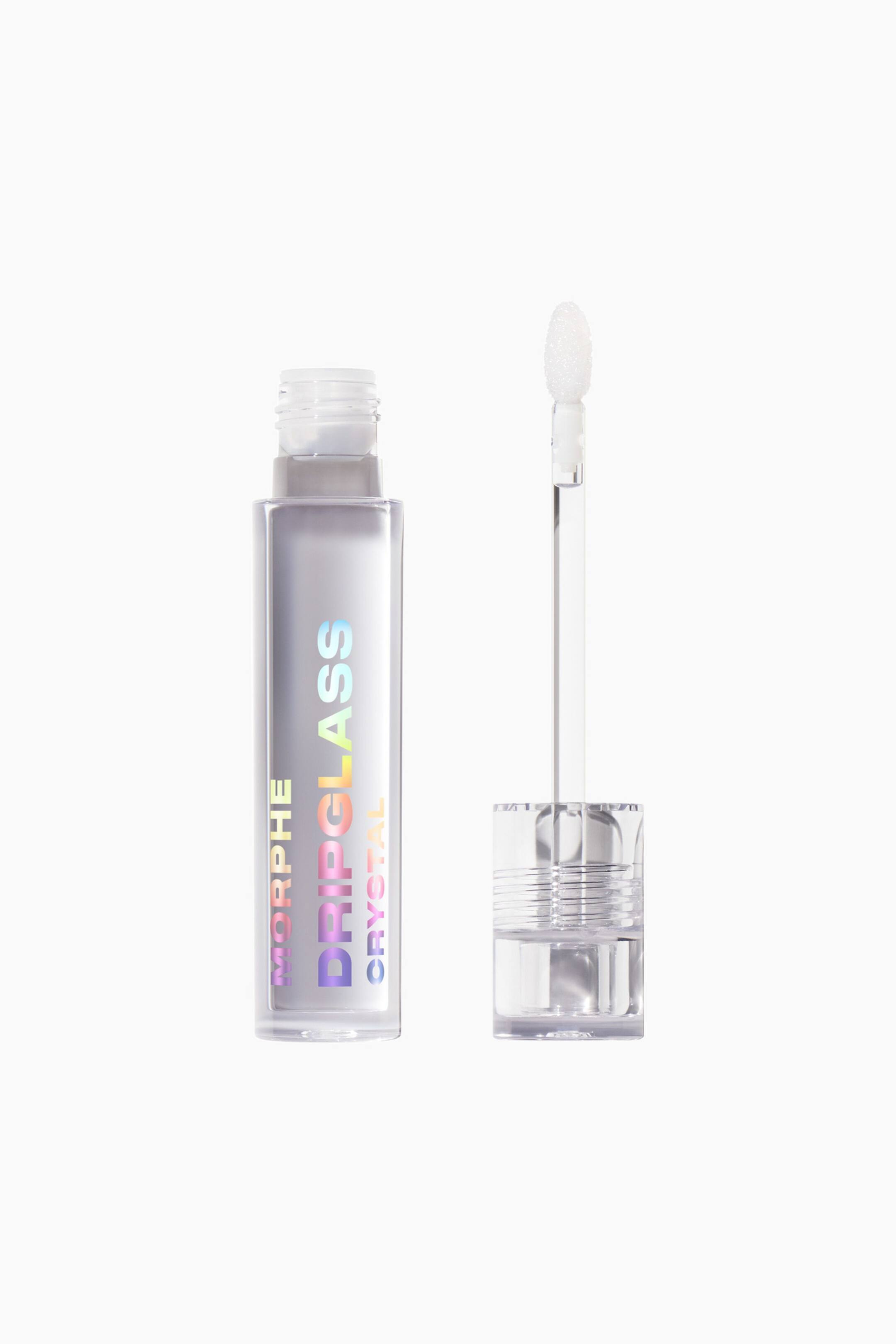 Vis større bilde: Dripglass Crystal Lip Gloss vises som et åpent sett, med en klar, firkantet flaske som står oppreist ved siden av den avtakne applikatorstaven. Flasken viser vertikal, iriserende tekst som leser «MORPHE DRIPGLASS CRYSTAL» over en semitransparent formel, mens staven står oppreist med en klar, riflet kork og en hvit doe-foot-applikator.