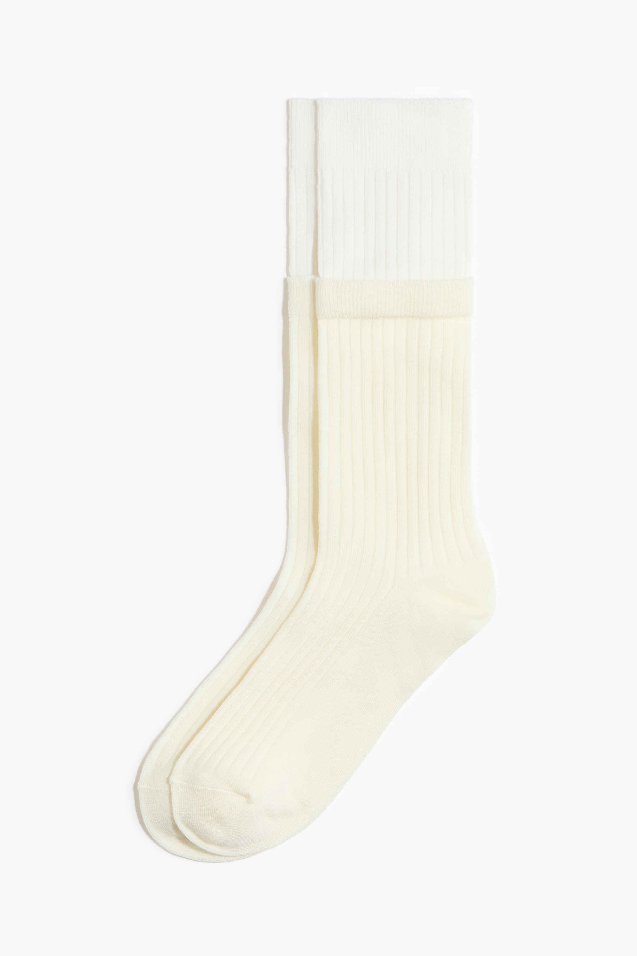 View larger image: A pair of light cream socks features a ribbed texture throughout, finished with a brighter white band at the top.