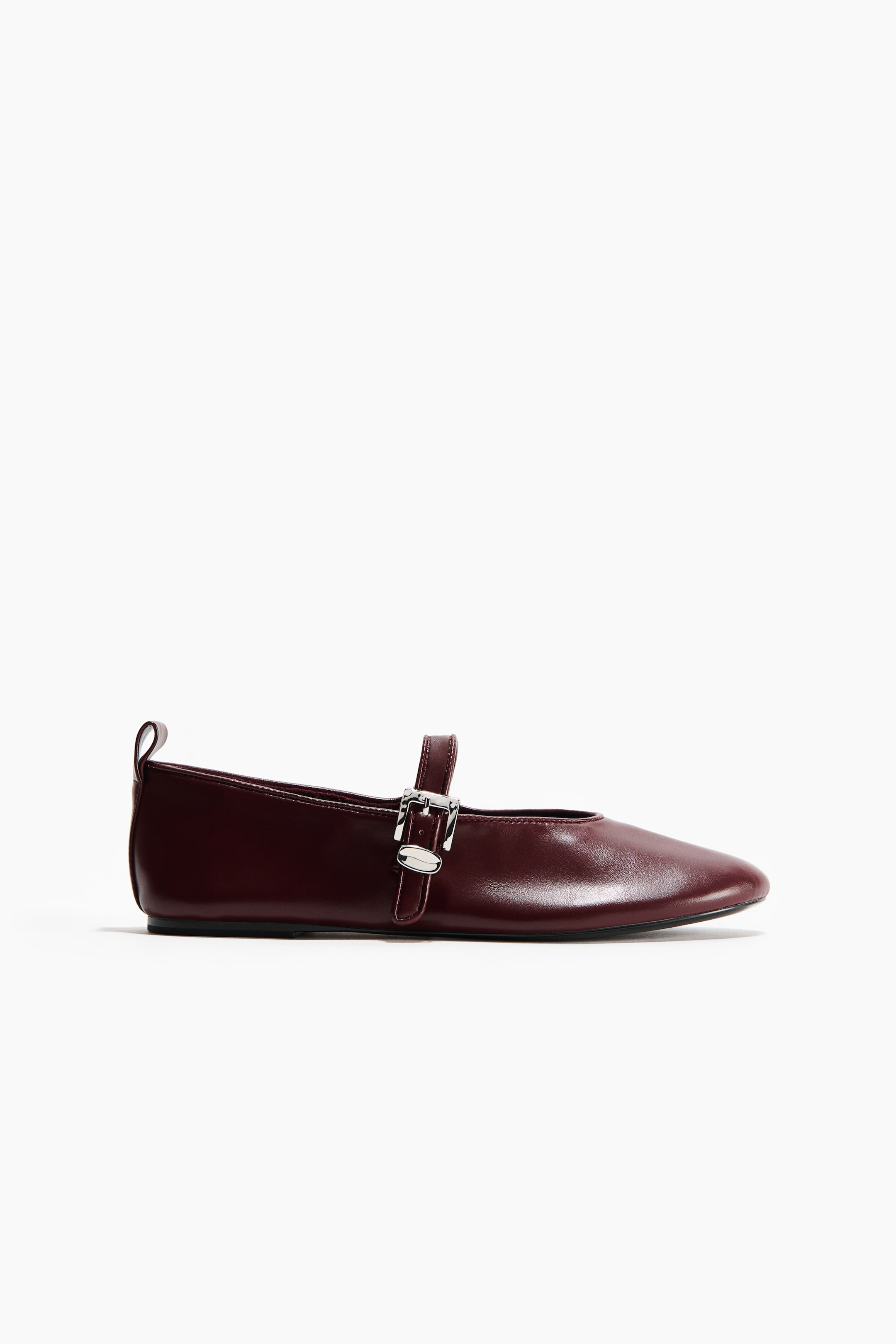Ver imagen más grande: Un zapato plano estilo Mary Jane en color burdeos está orientado hacia la derecha, con una punta redondeada y una suela delgada de color negro. Una única correa cruza el empeine, asegurada por una hebilla de tono plateado, con una pequeña lengüeta visible en el talón trasero.