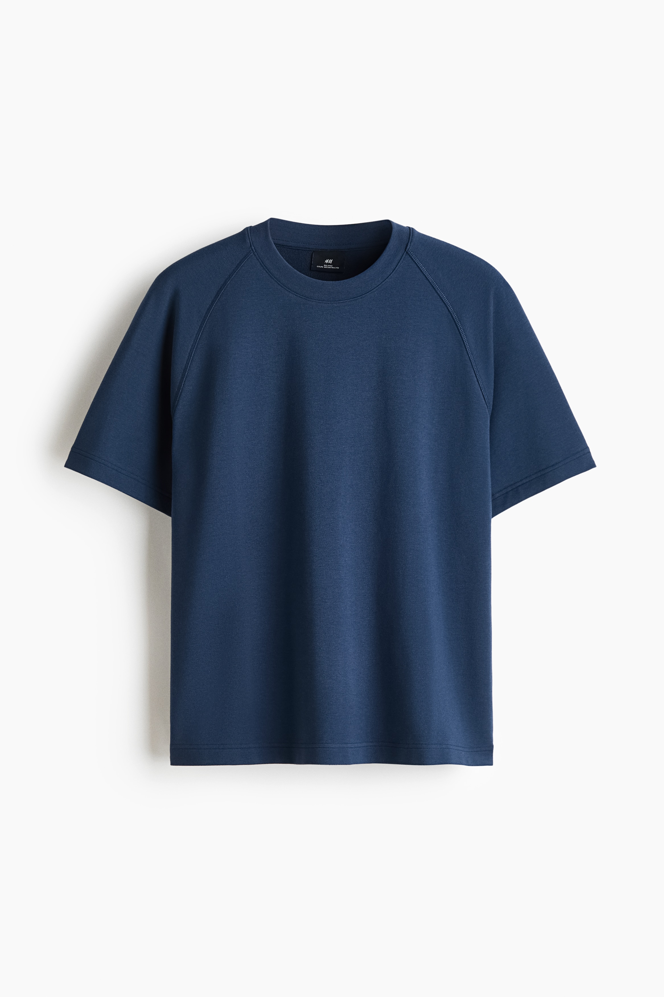 Le mannequin porte un t-shirt en jersey Ã©pais bleu foncÃ©, de coupe dÃ©contractÃ©e, dotÃ© dâun col rond avec bord-cÃ´te et de manches raglan courtes. Le t-shirt est agencÃ© avec un bas assorti Ã  cordon de serrage.