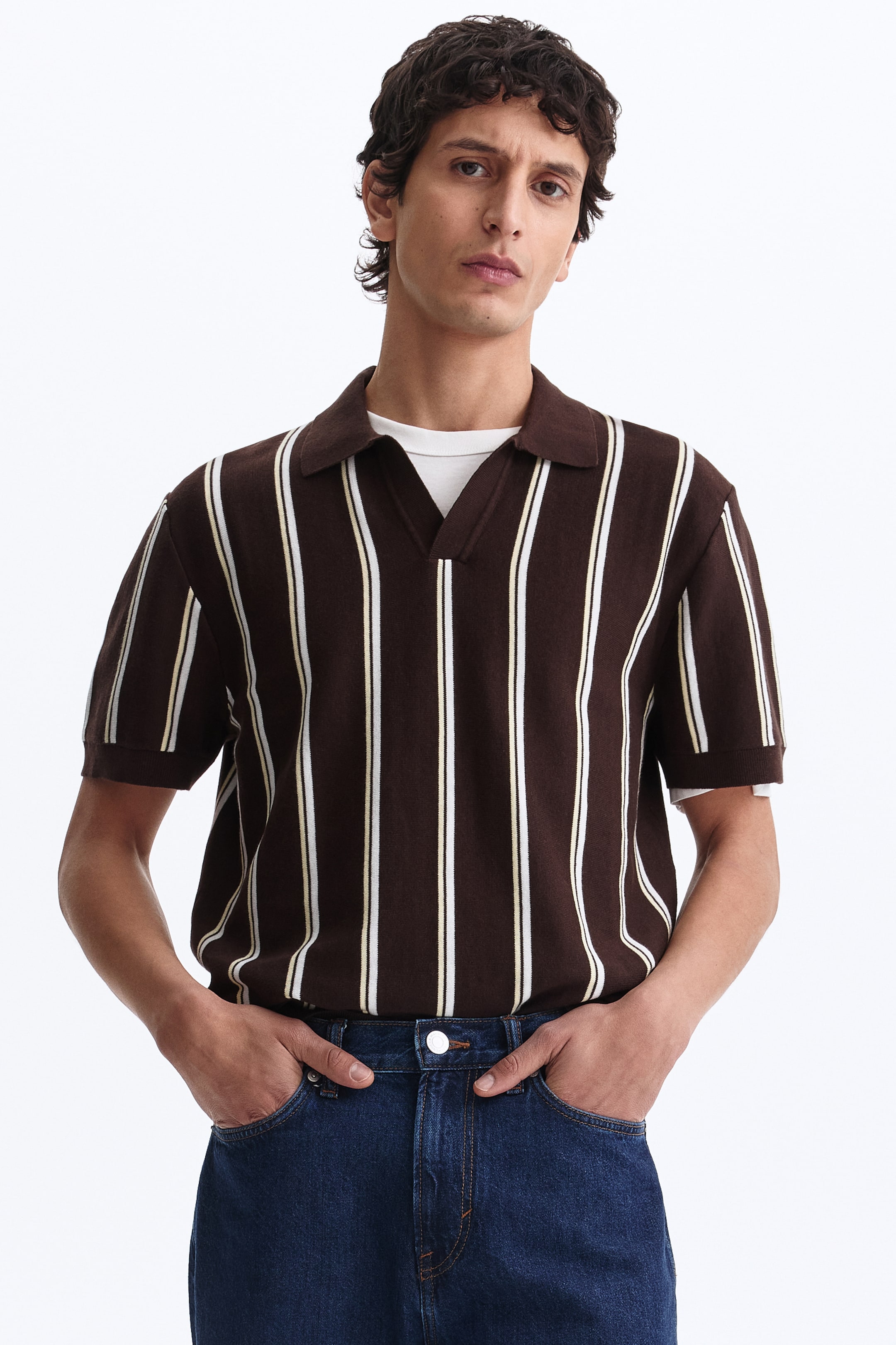 View larger image: A brown knit polo shirt features vertical white and light yellow stripes. It has a spread collar, a V-neck opening, and short sleeves, and is layered over a white T-shirt.