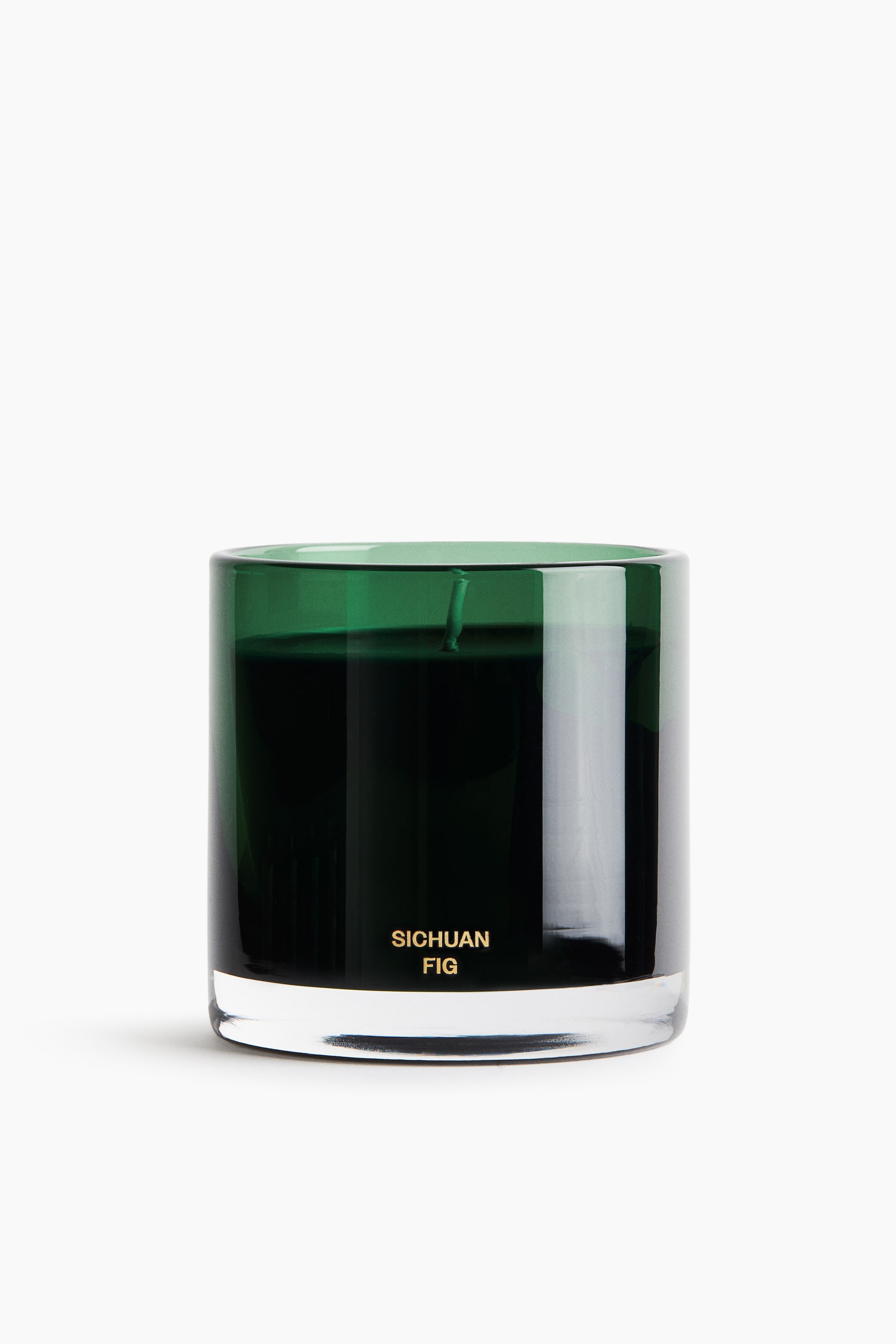View larger image: A scented candle in a cylindrical dark green glass vessel is shown front-facing, featuring a thick clear base and gold lettering that reads "SICHUAN FIG" on the lower portion. Inside, dark wax is visible with a single wick extending from the centre.