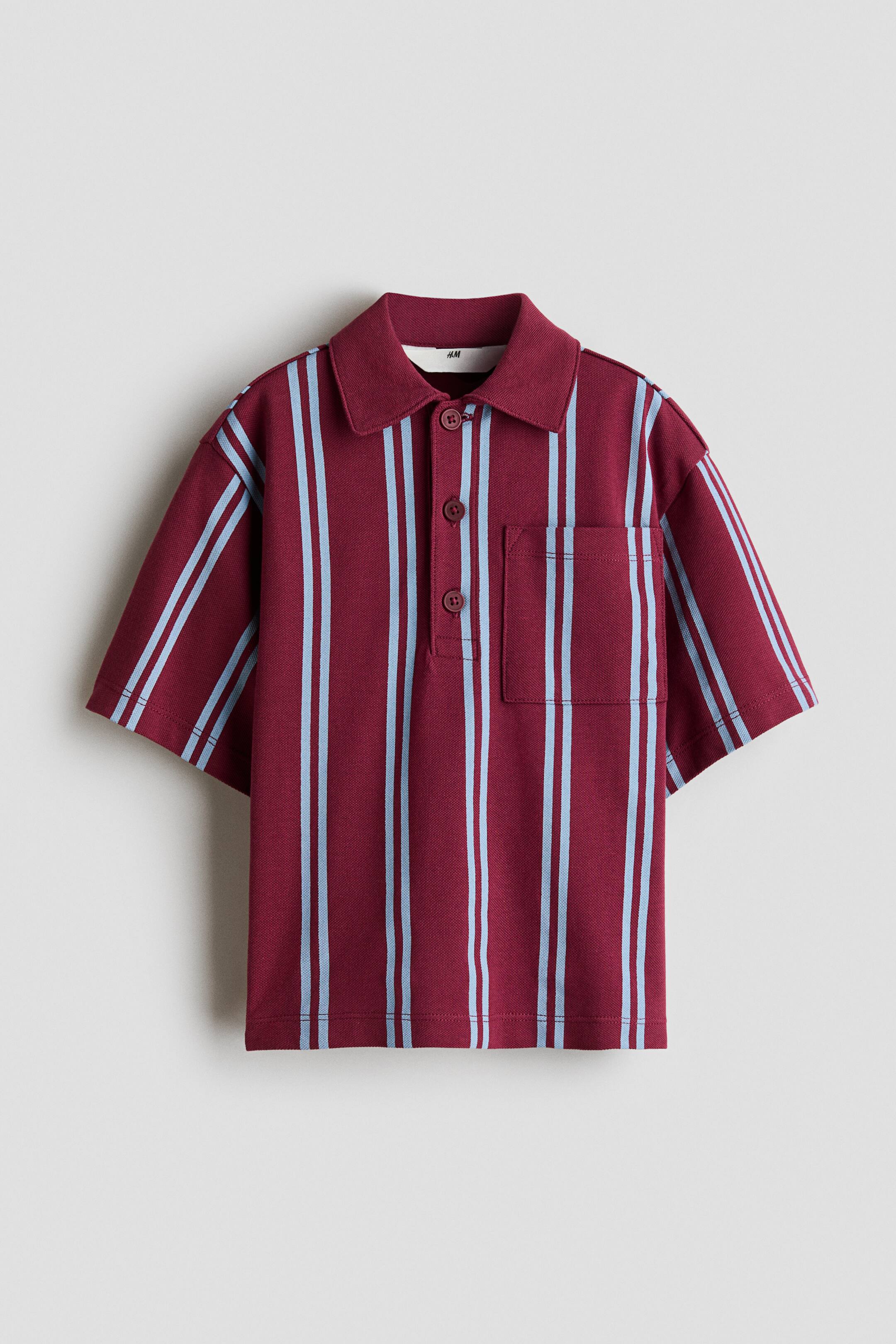 View larger image: A burgundy and light blue vertically striped polo shirt featuring a pointed collar, a three-button placket with matching burgundy buttons, short sleeves, and a patch pocket on the left chest.