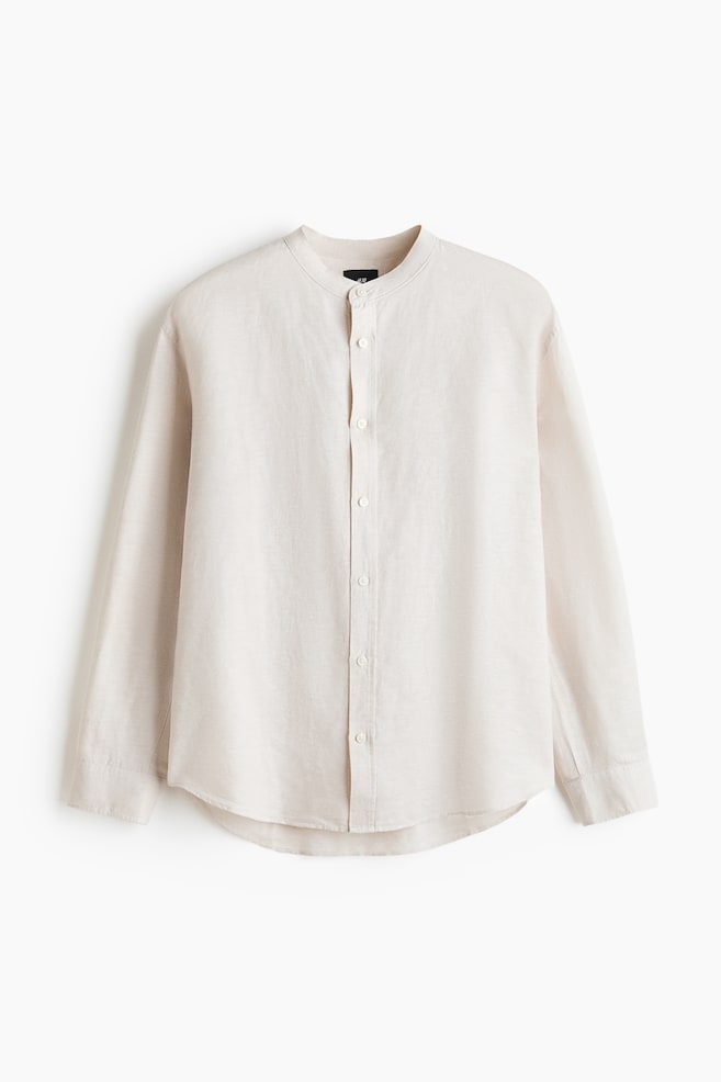 A light-coloured, relaxed-fit shirt is displaying its front, showcasing a band collar, a classic button-front placket with white buttons, long sleeves with buttoned cuffs, and a rounded hem. The shirt is showing a visibly textured linen and cotton blend fabric. - 1