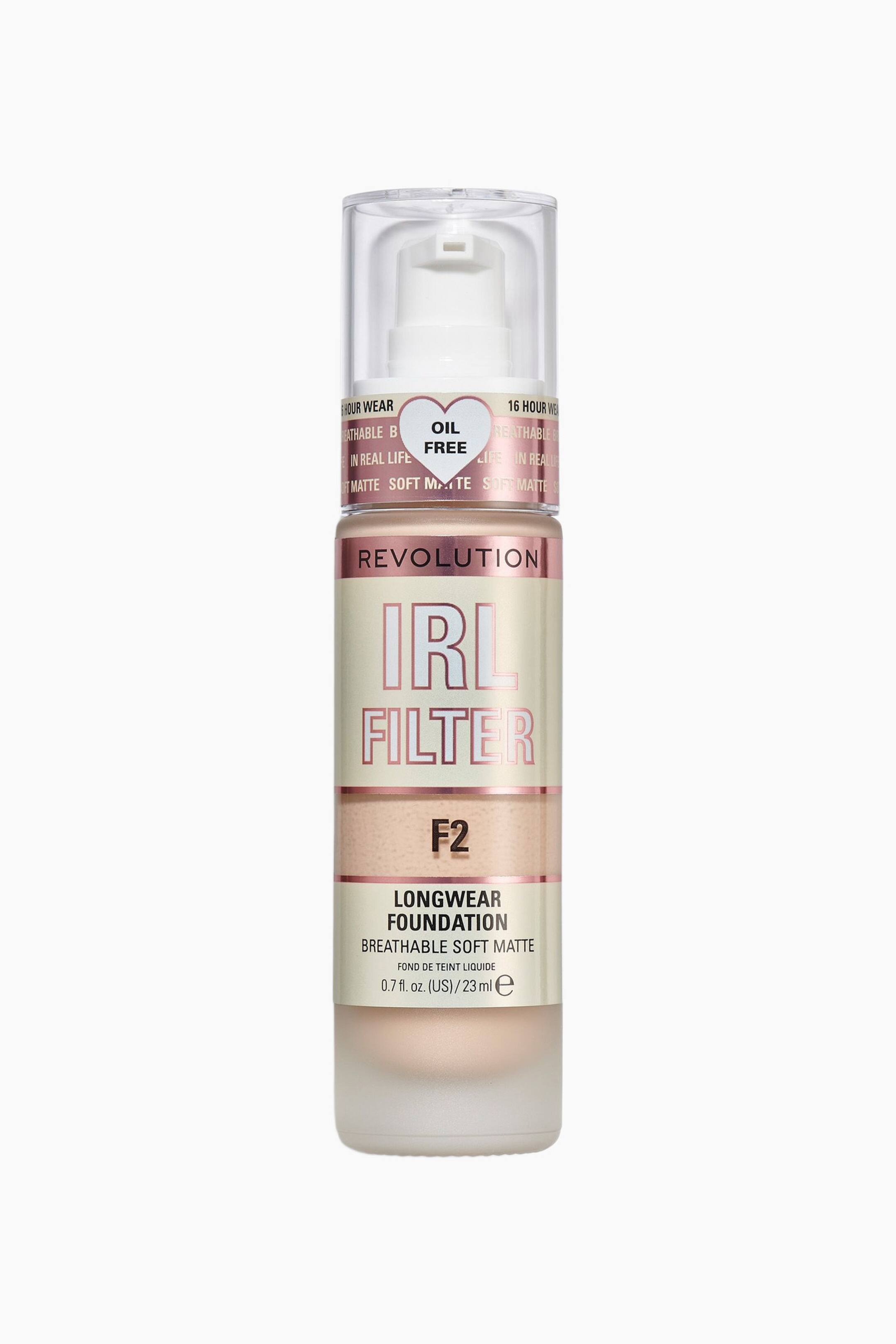 Größeres Bild ansehen: Die Revolution IRL Filter Longwear Foundation steht aufrecht in einer frontalen Ansicht und zeigt eine zylindrische Flasche mit mattiertem Boden, der einen hellbeigen Foundation-Ton sichtbar macht. Sie verfügt über einen weißen Pumpverschluss, der von einer transparenten Kappe umschlossen ist, sowie über ein roségoldenes Etikett mit den Aufschriften „IRL FILTER“ und „LONGWEAR FOUNDATION“ neben dem Farbcode „F2“.