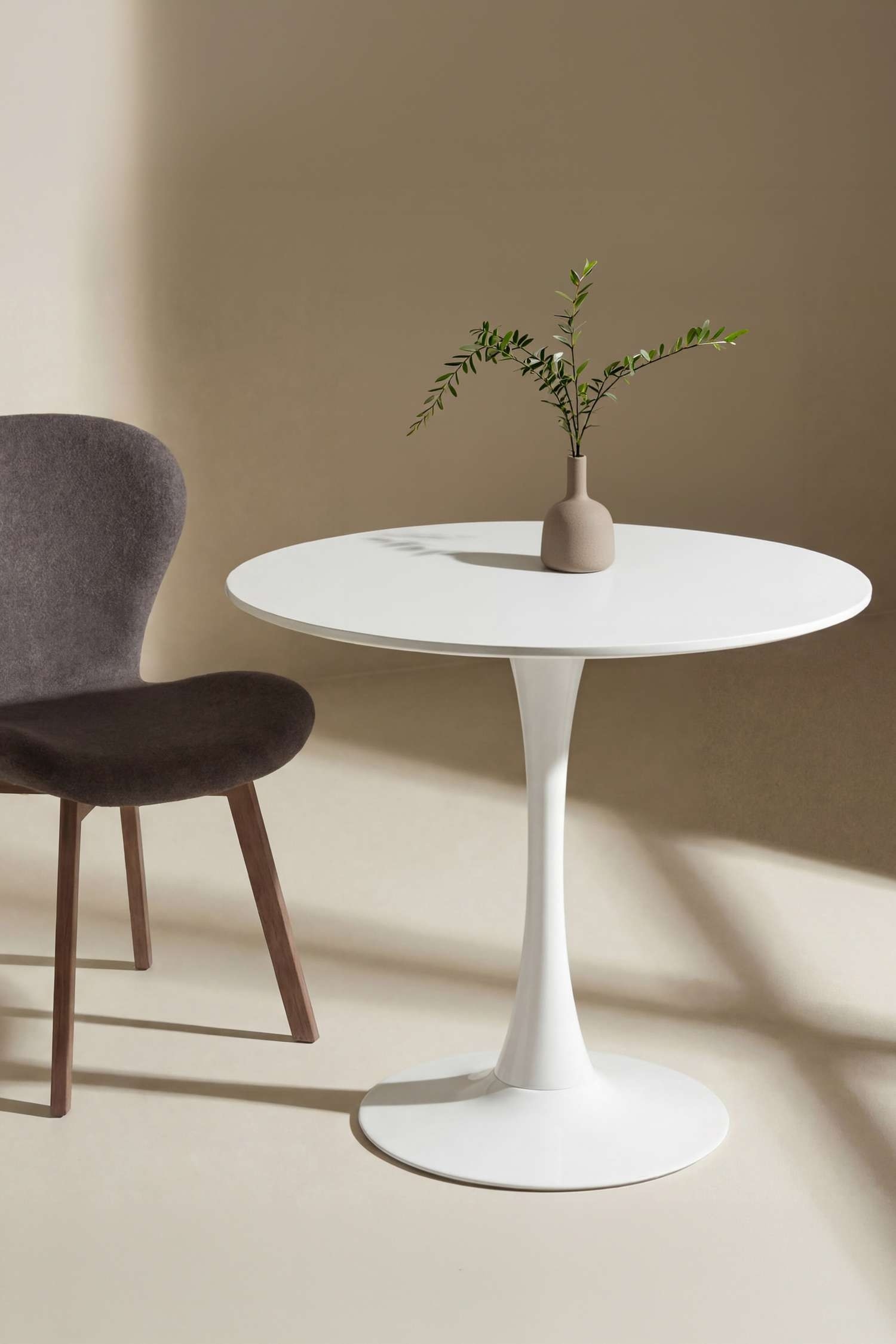 Een witte zuiltafel staat rechtop en toont een glad, rond tafelblad dat wordt ondersteund door een enkele, slanke steel in tulpenstijl die uitloopt in een ronde voet. De tafel is vanuit recht van voren te zien met een glanzende witte afwerking.