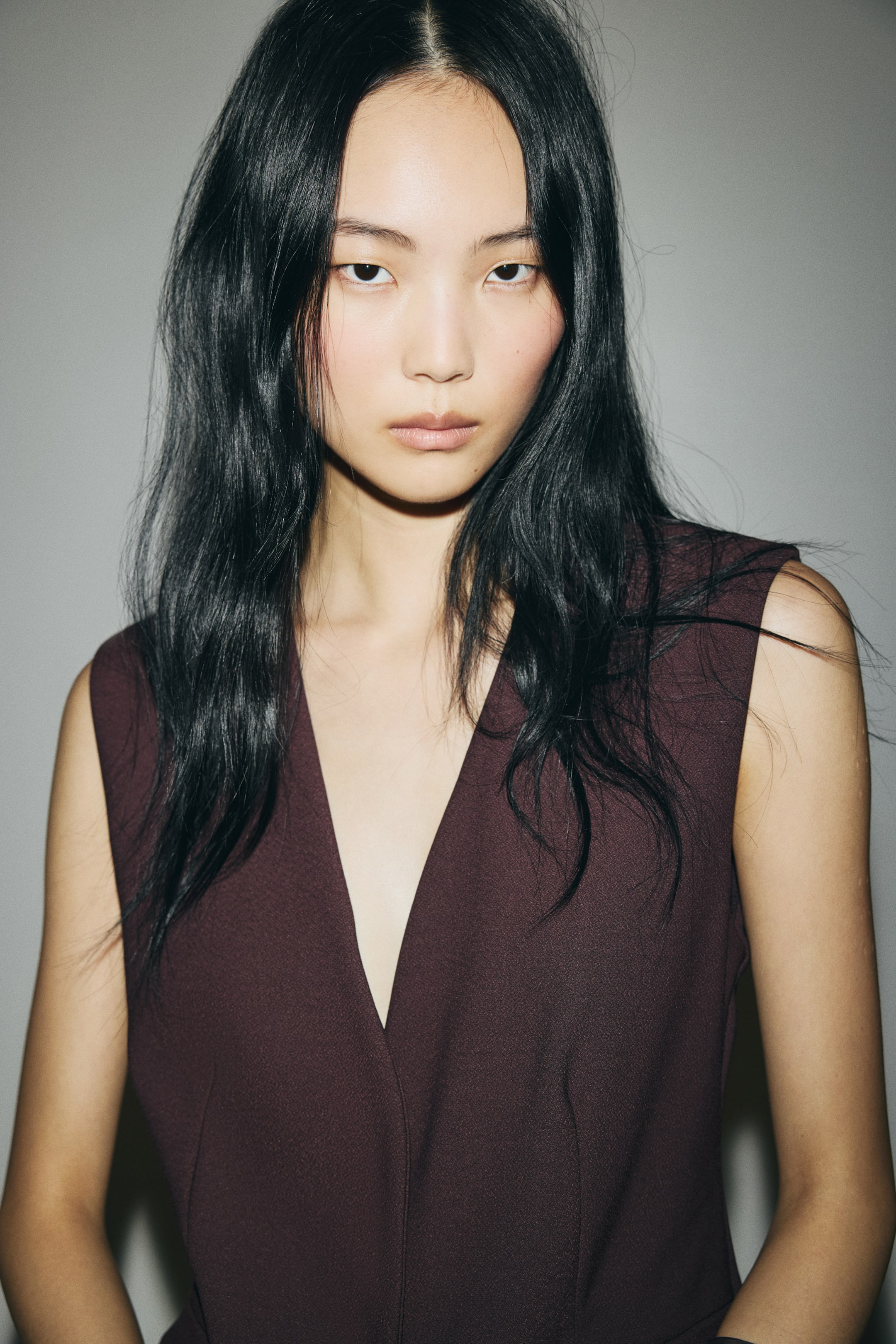 View larger image: A dark burgundy sleeveless garment is featuring a deep V-neckline and tailored vertical seaming down the front.