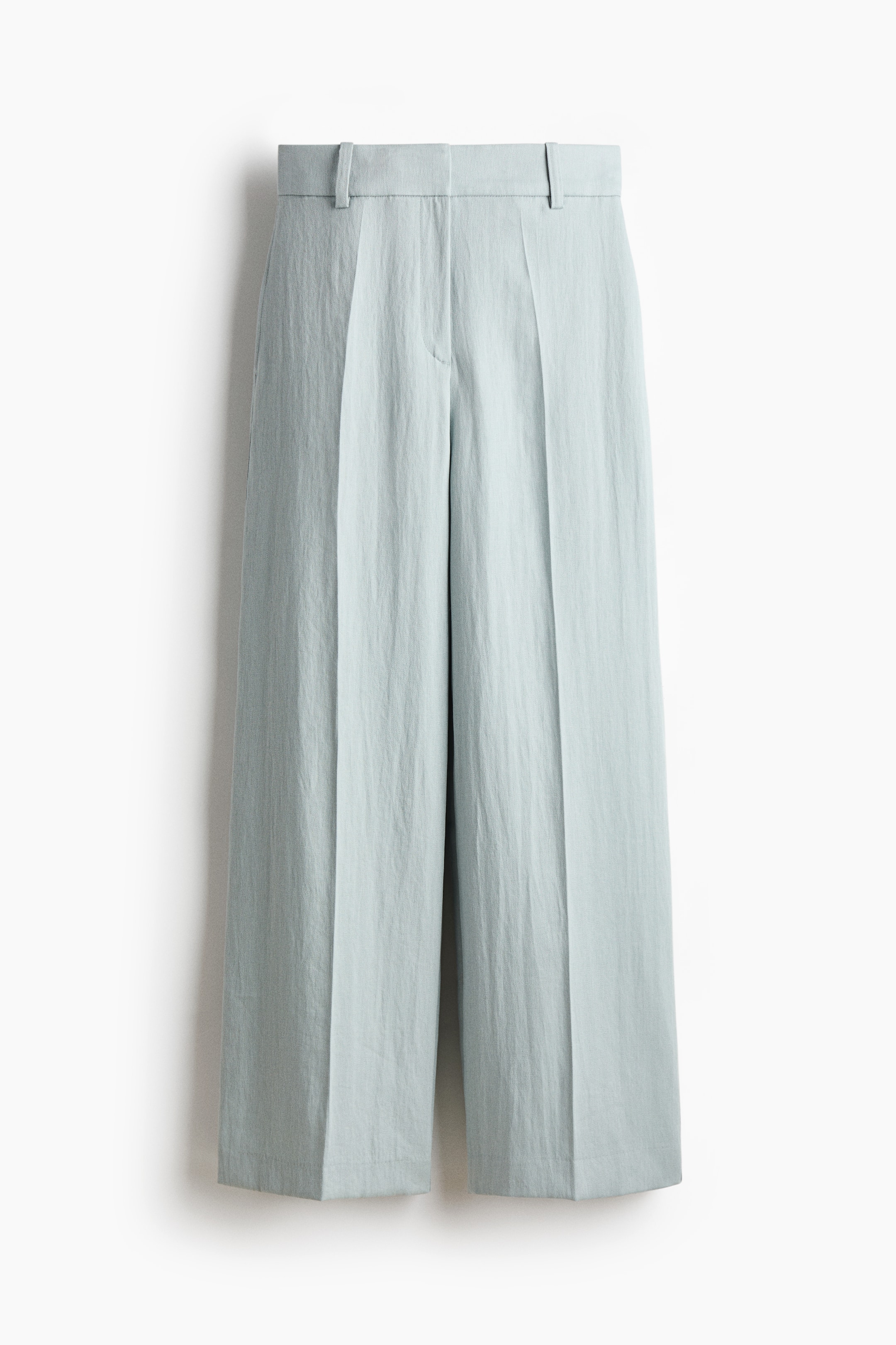 Agrandir l'image: Vue de FACE du pantalon sur mesure en tissu tissé bleu clair. Il présente une taille haute avec une fermeture éclair, des poches latérales discrètes et des jambes larges avec des plis sur le devant.