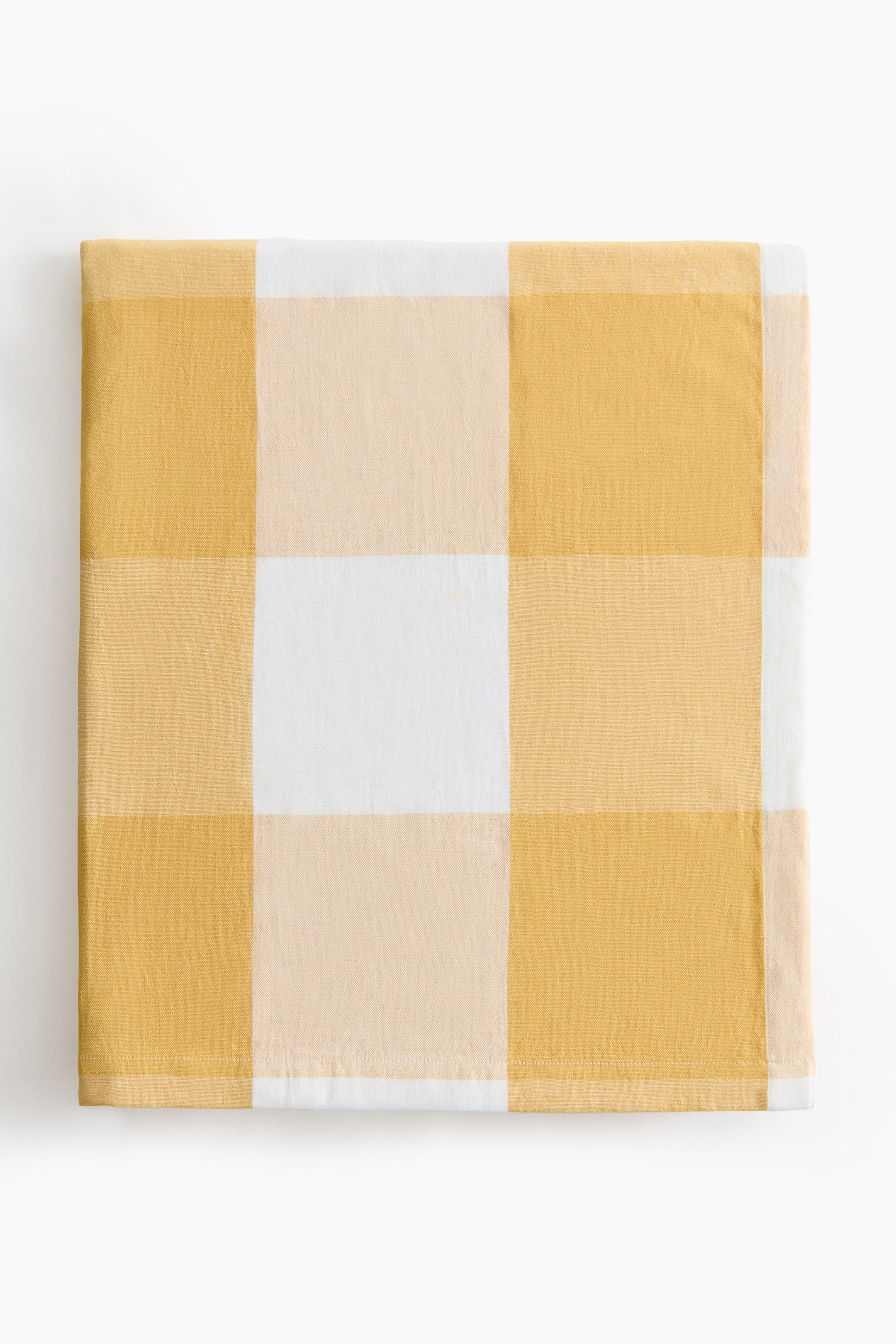 Voir une image plus grande: La nappe classique est étendue à plat, affichant un grand motif à carreaux blanc, jaune pâle et jaune. Elle est faite d'un mélange de lin et de coton, avec un tissage apparent à motifs.