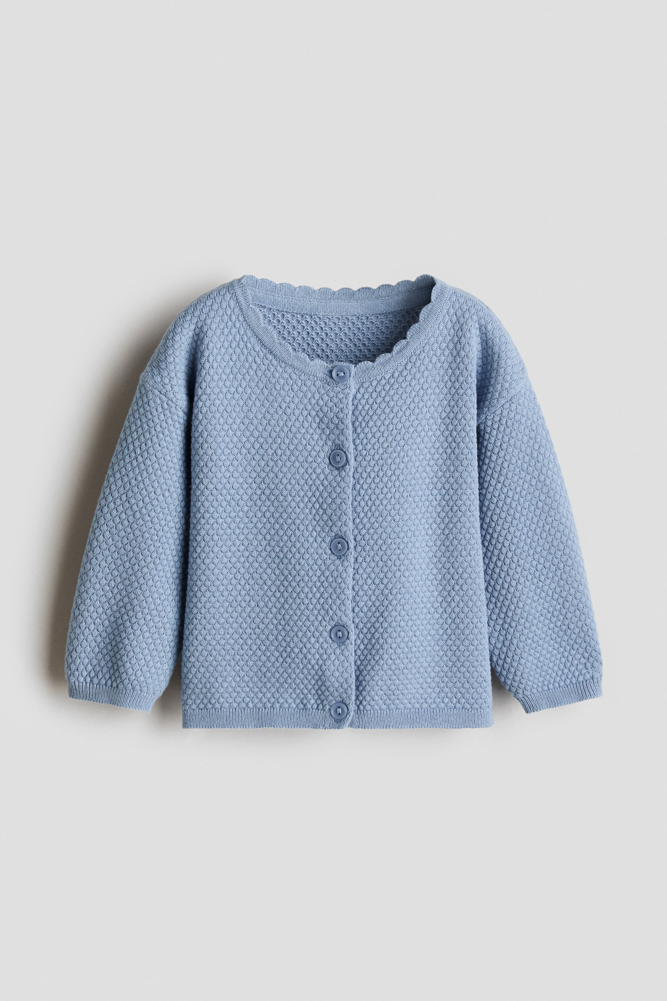 Visualizza immagine più grande: Un cardigan blu mostra la sua vista frontale, con un motivo a maglia testurizzata, uno scollo rotondo smerlato e bottoni tono su tono lungo la parte anteriore. Sono visibili le spalle scese, mentre un bordo a costine strette rifinisce polsini e orlo.