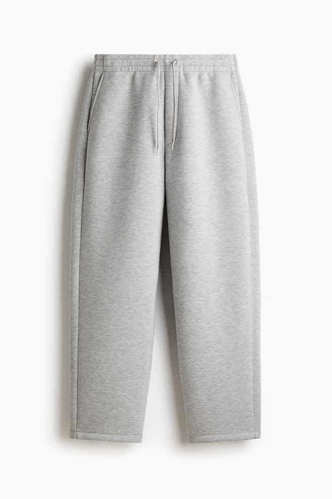 Grey sweatpants are hanging flat, facing forward. They are featuring an elasticated waistband with a visible drawstring, inset side pockets, and straight legs with plain hems. - 1